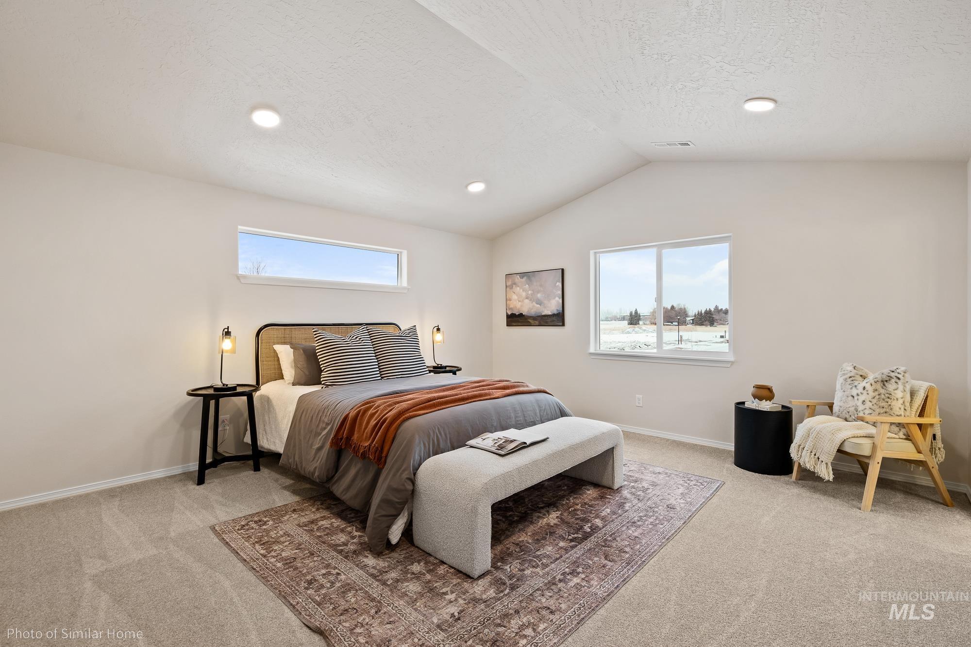 Bedroom with multiple windows, light colored carpet, vaulted ceiling, recessed lighting, and a textured ceiling