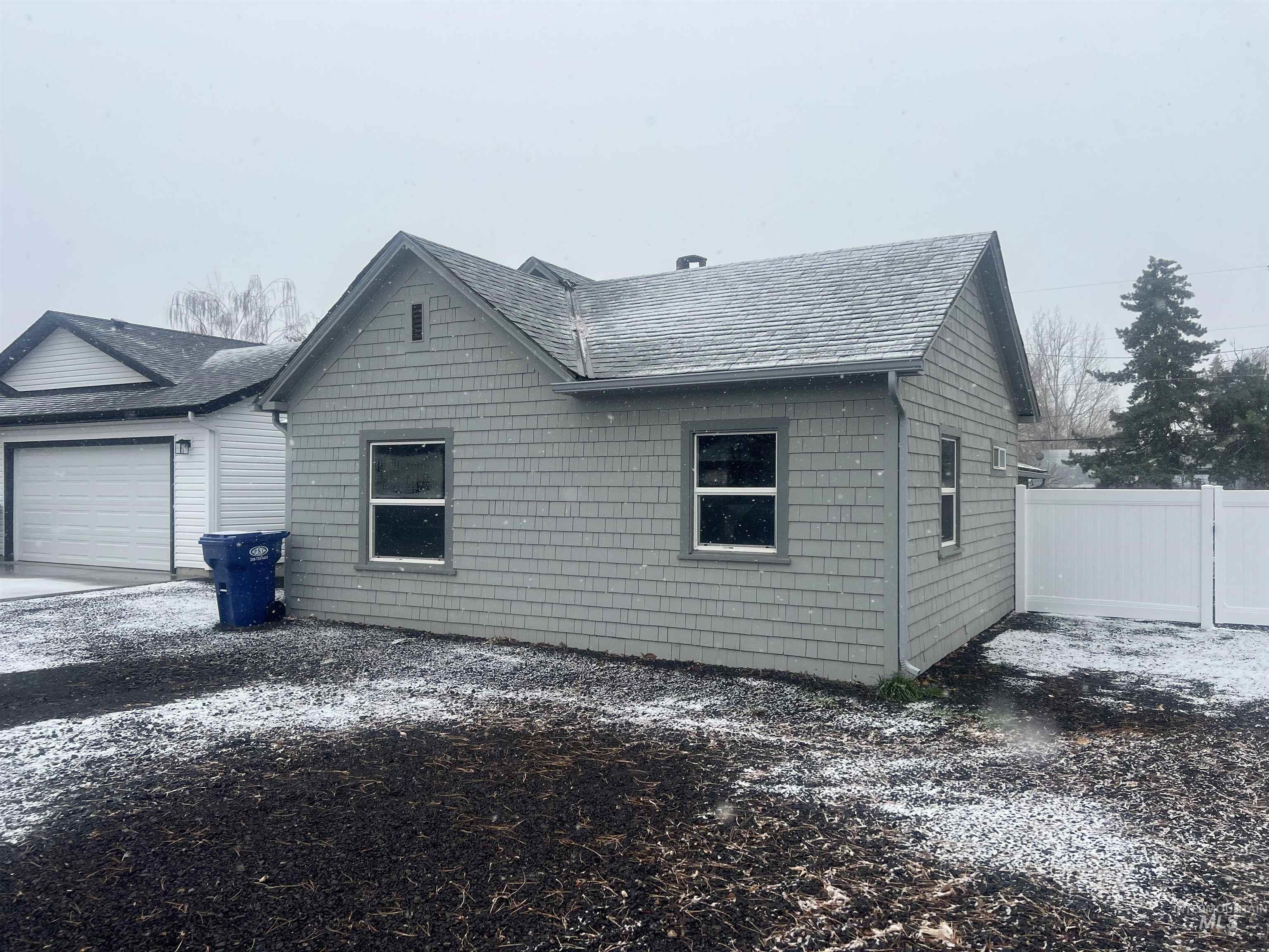 View of side of property with a garage and roof with shingles