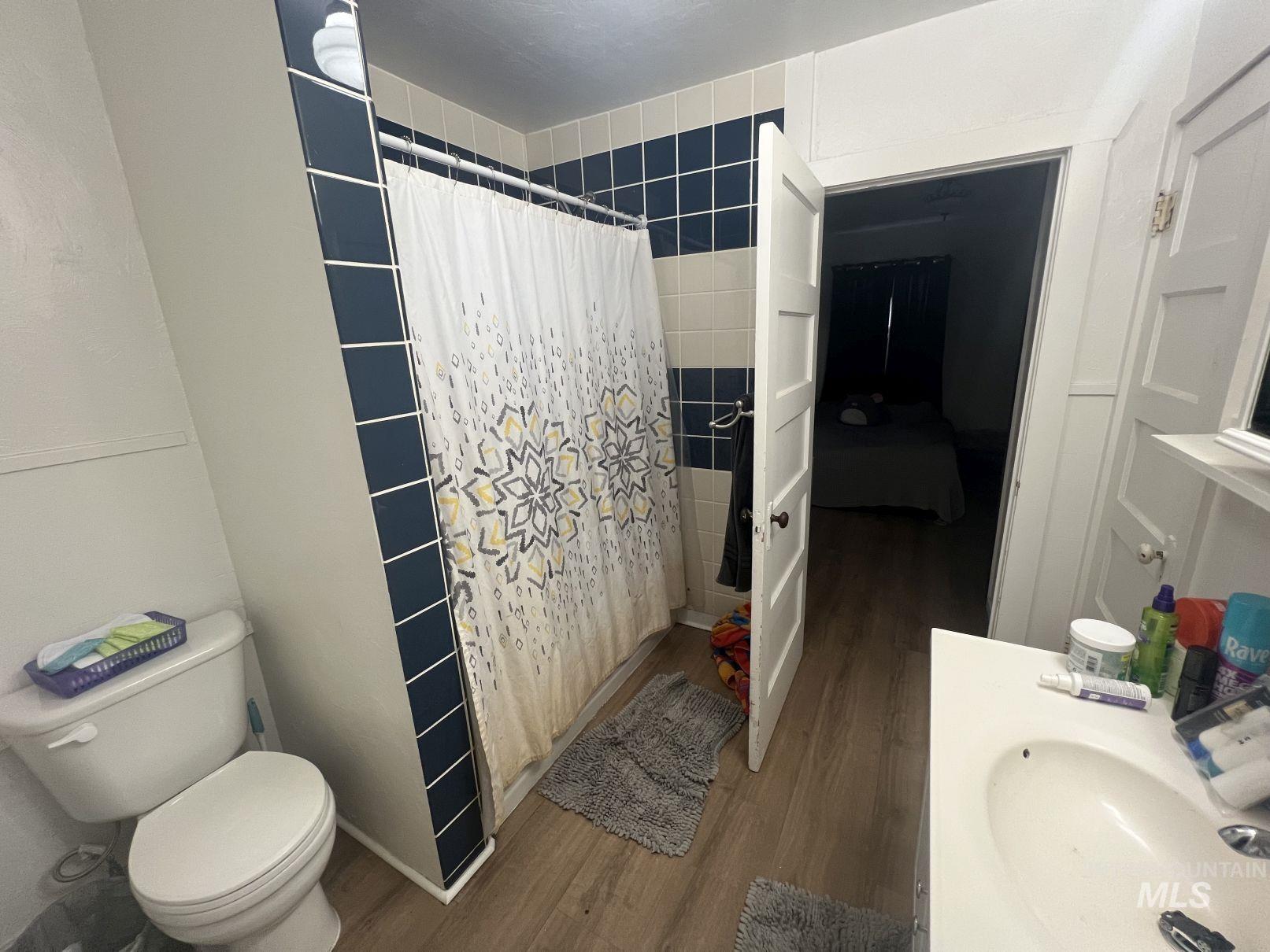 Full bath with dark wood-style flooring, vanity, a tile shower, and connected bathroom