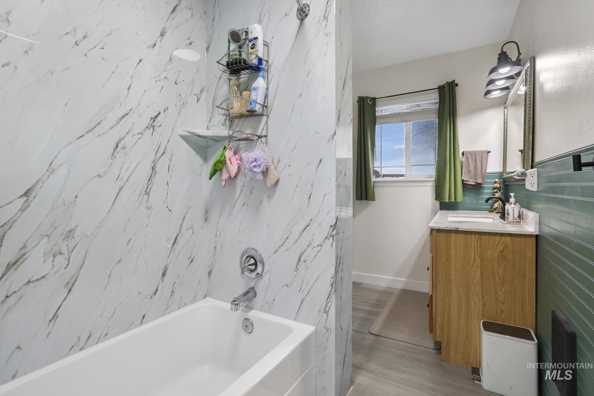 Bathroom with vanity, shower / tub combination, and light wood-style flooring