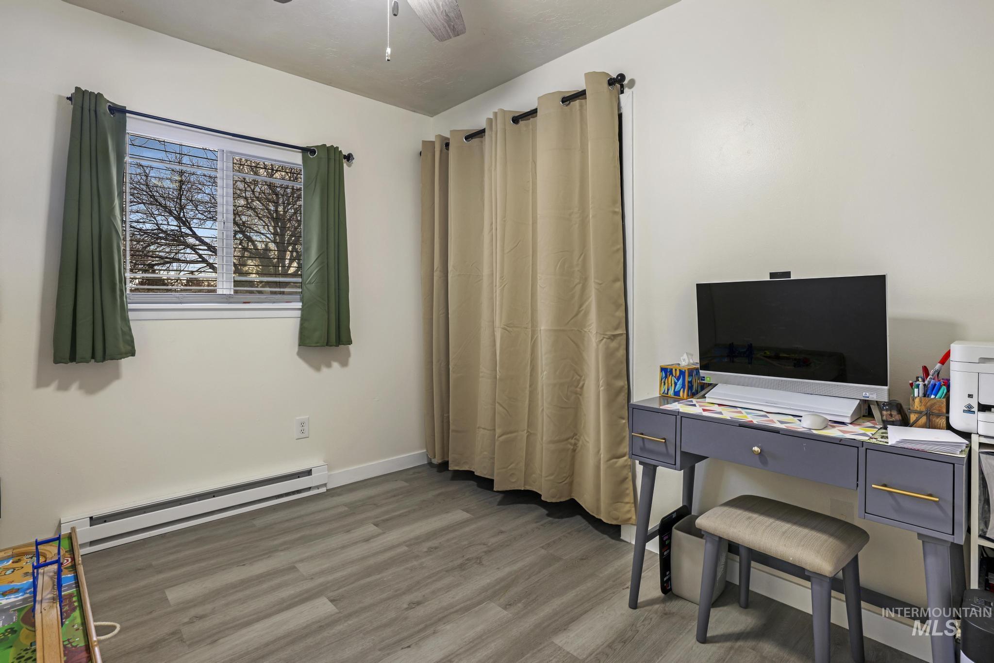 Office area featuring baseboard heating, a ceiling fan, and light wood-style floors