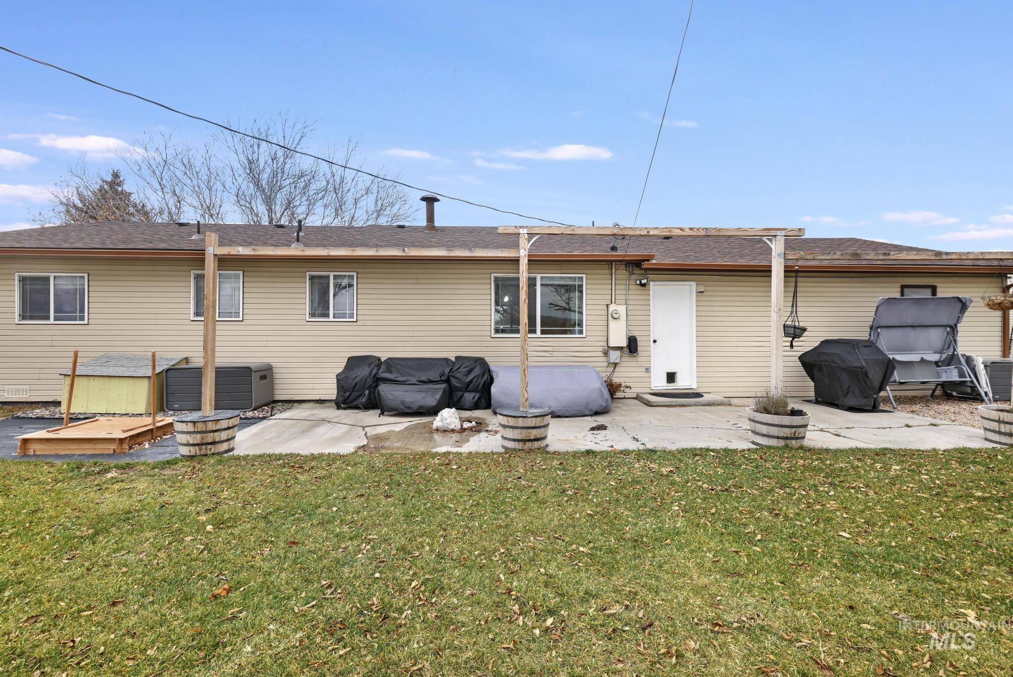 Back of house with a patio area, a yard, and a shingled roof