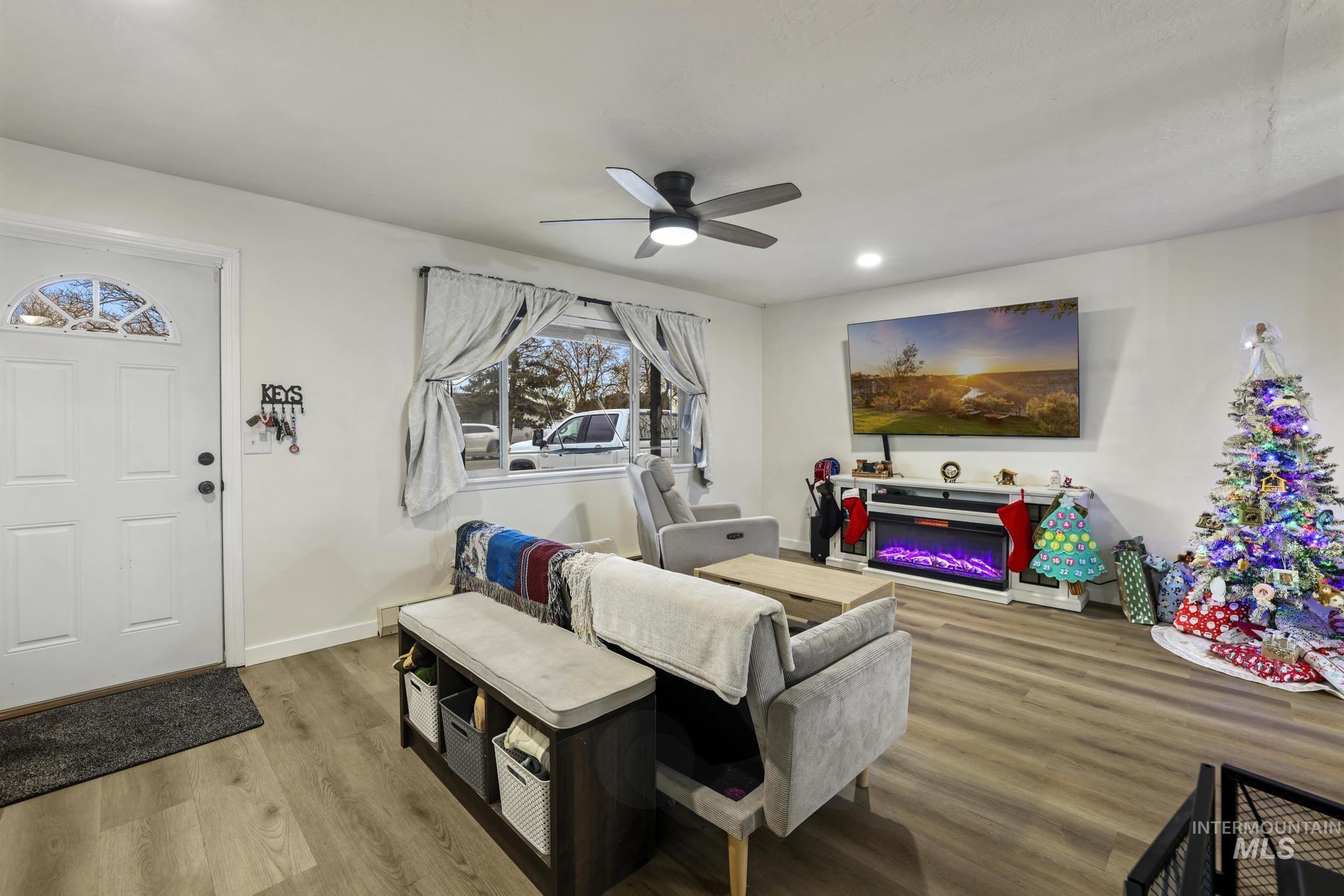 Living area with wood finished floors, a glass covered fireplace, a ceiling fan, and recessed lighting