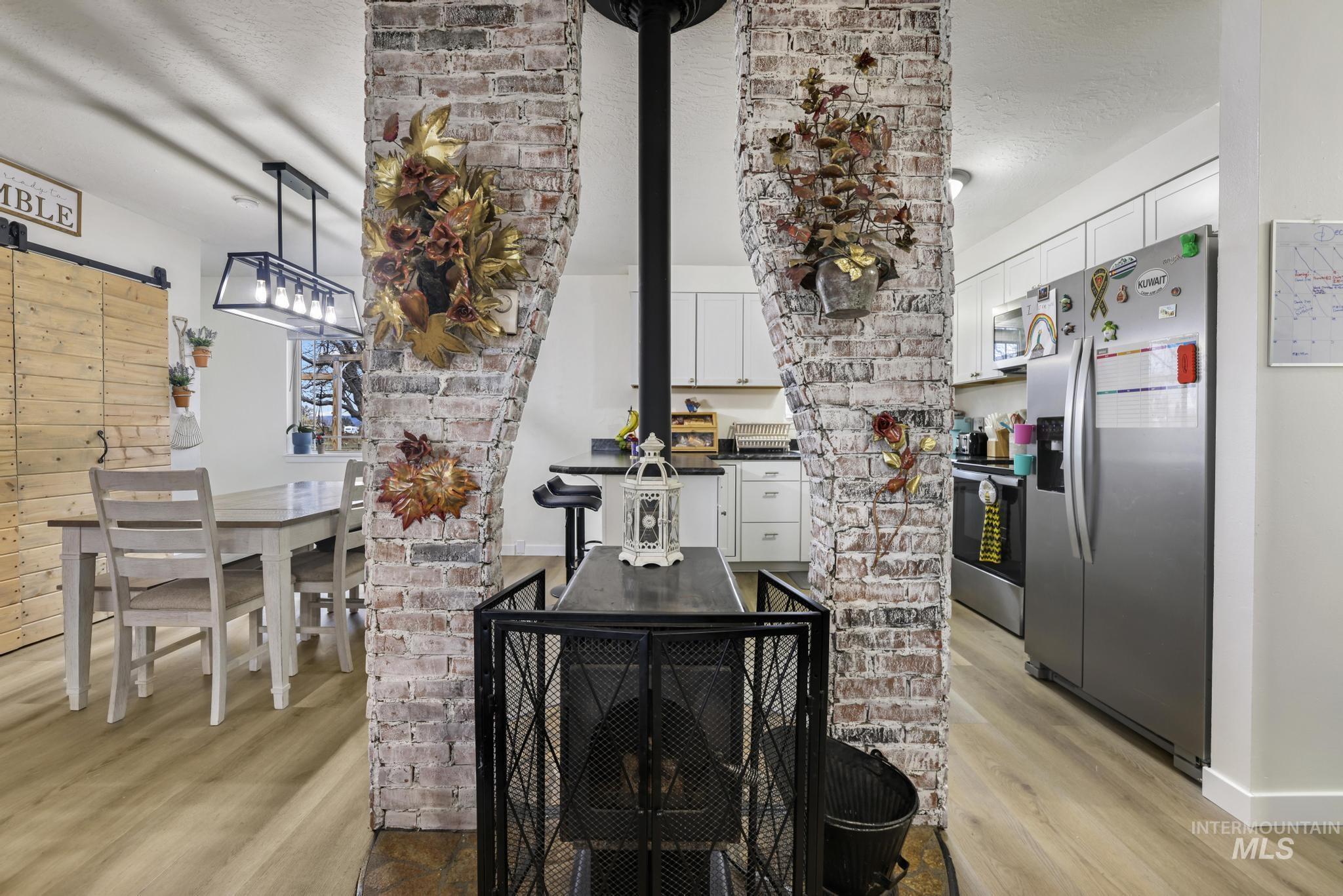 Detailed view of appliances with stainless steel finishes, a barn door, wood finished floors, and a textured ceiling