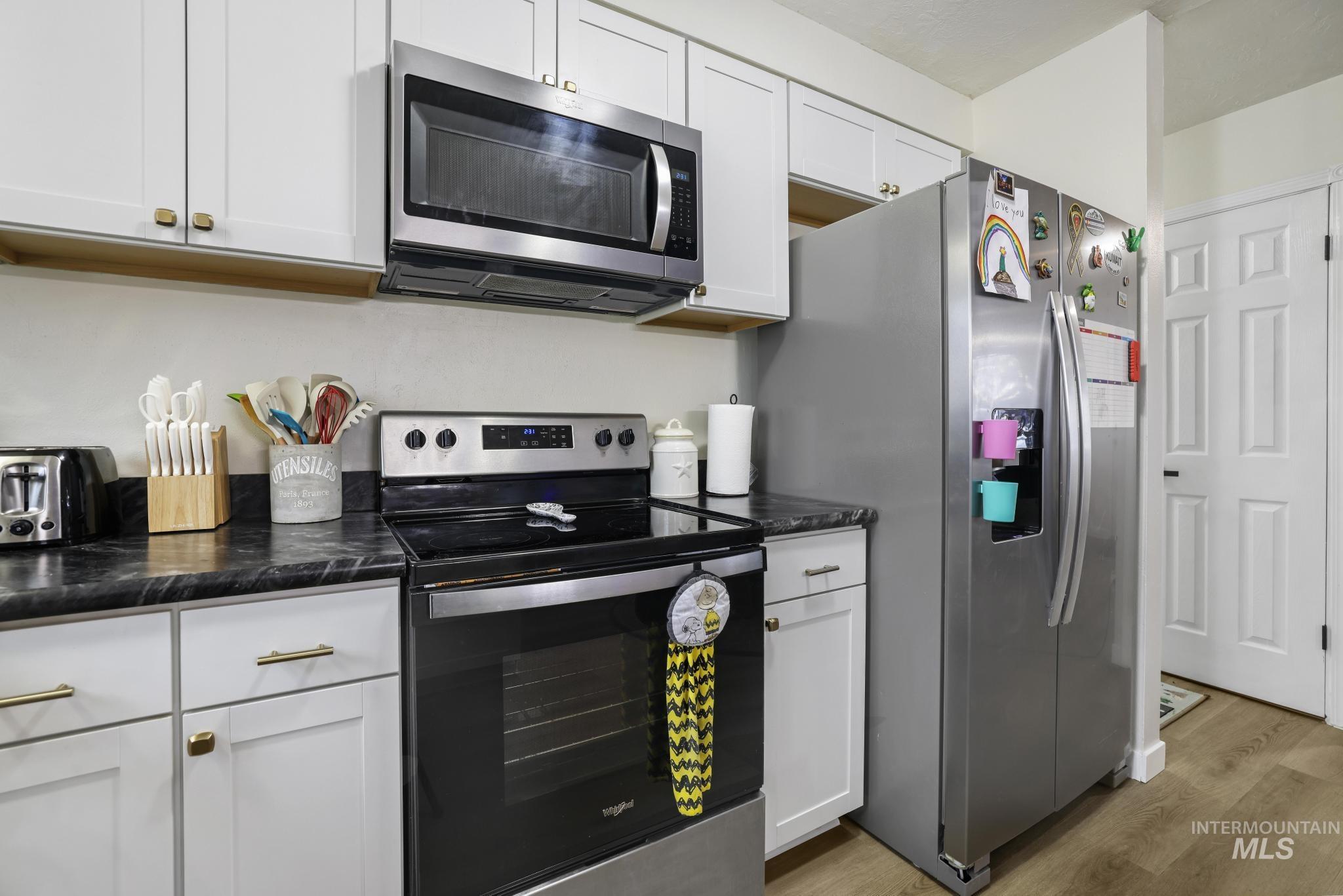 Kitchen featuring stainless steel appliances, light wood-type flooring, and white cabinets