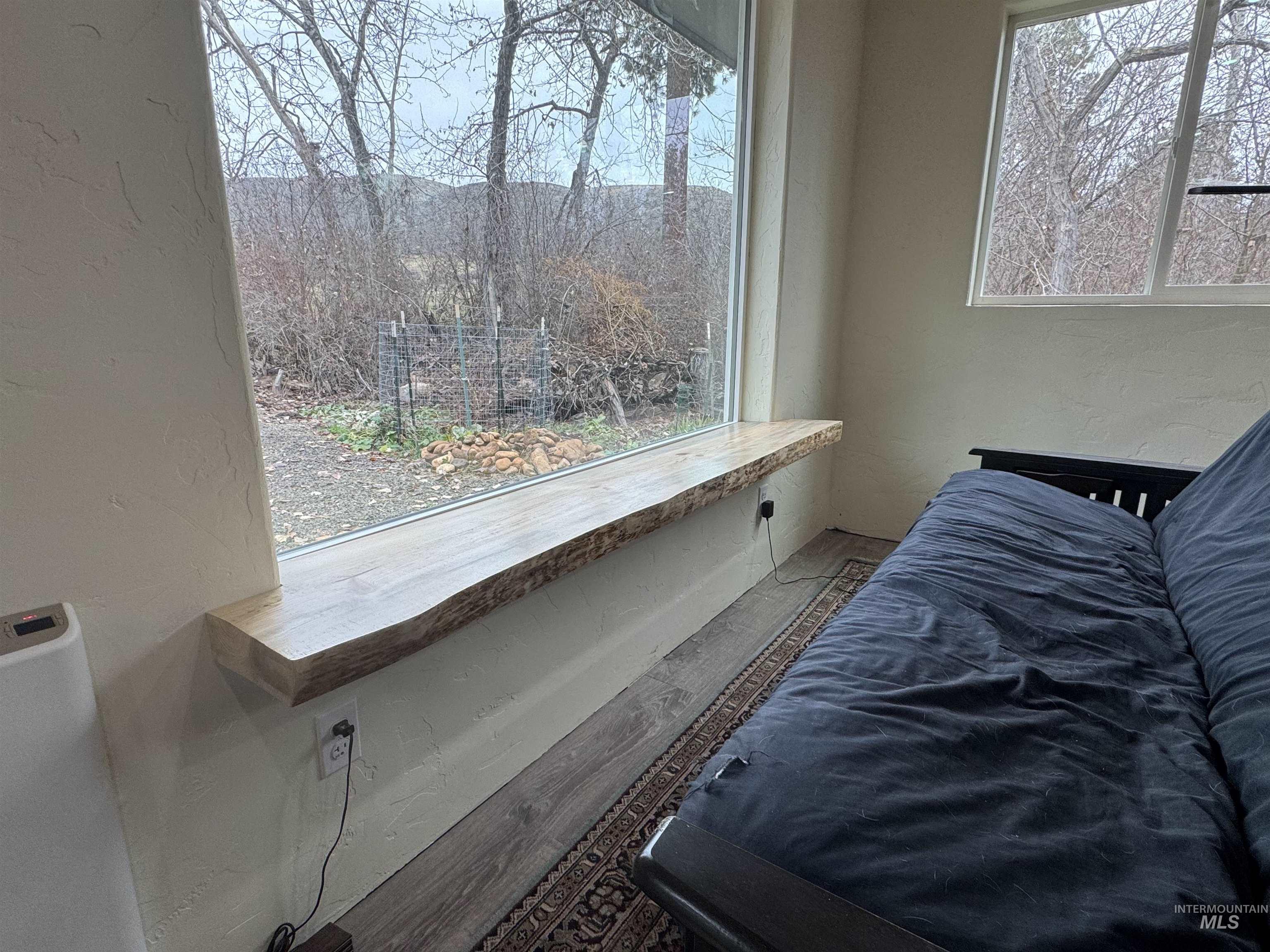 Family room off the main house, with multiple windows, a textured wall, and wood finished floors
