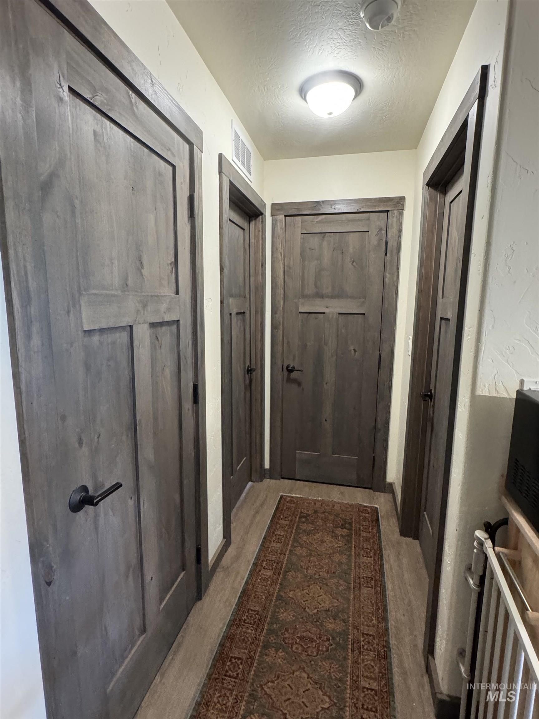 Doorway to outside with a textured ceiling and wood finished floors