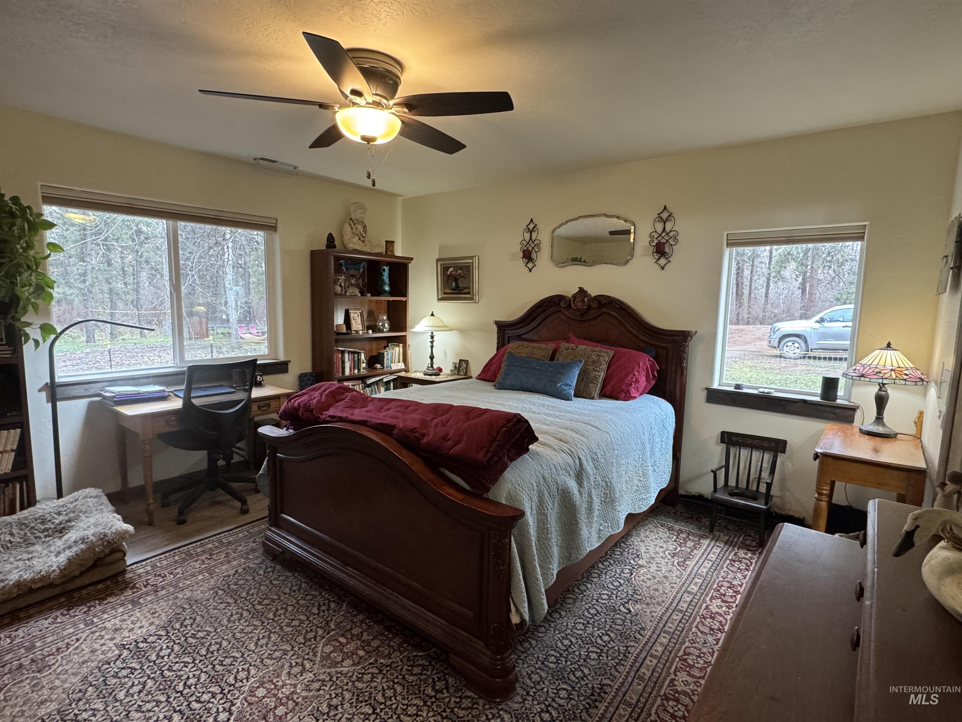 Bedroom with ceiling fan, multiple windows, and wood finished floors