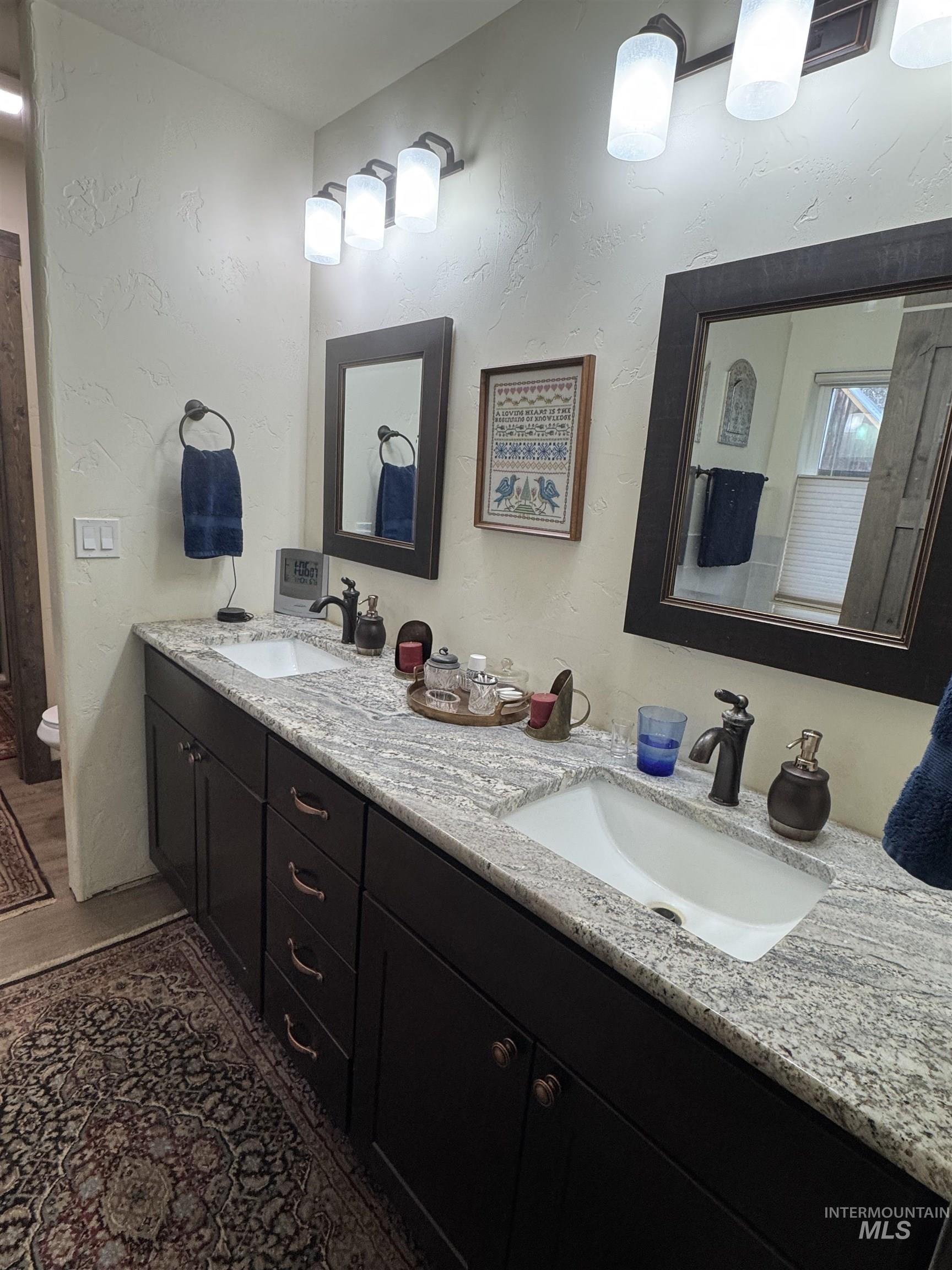 Bathroom featuring a textured wall and double vanity