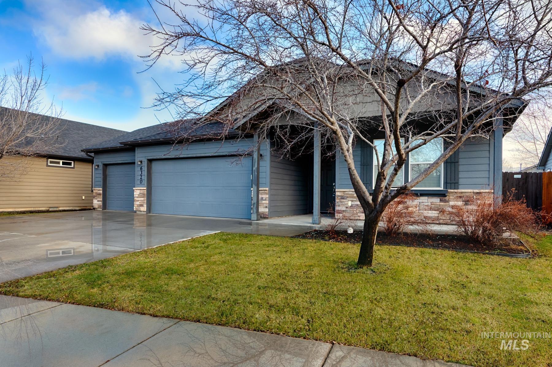 Ranch-style house featuring a front lawn, a garage, driveway, stone siding, and a porch