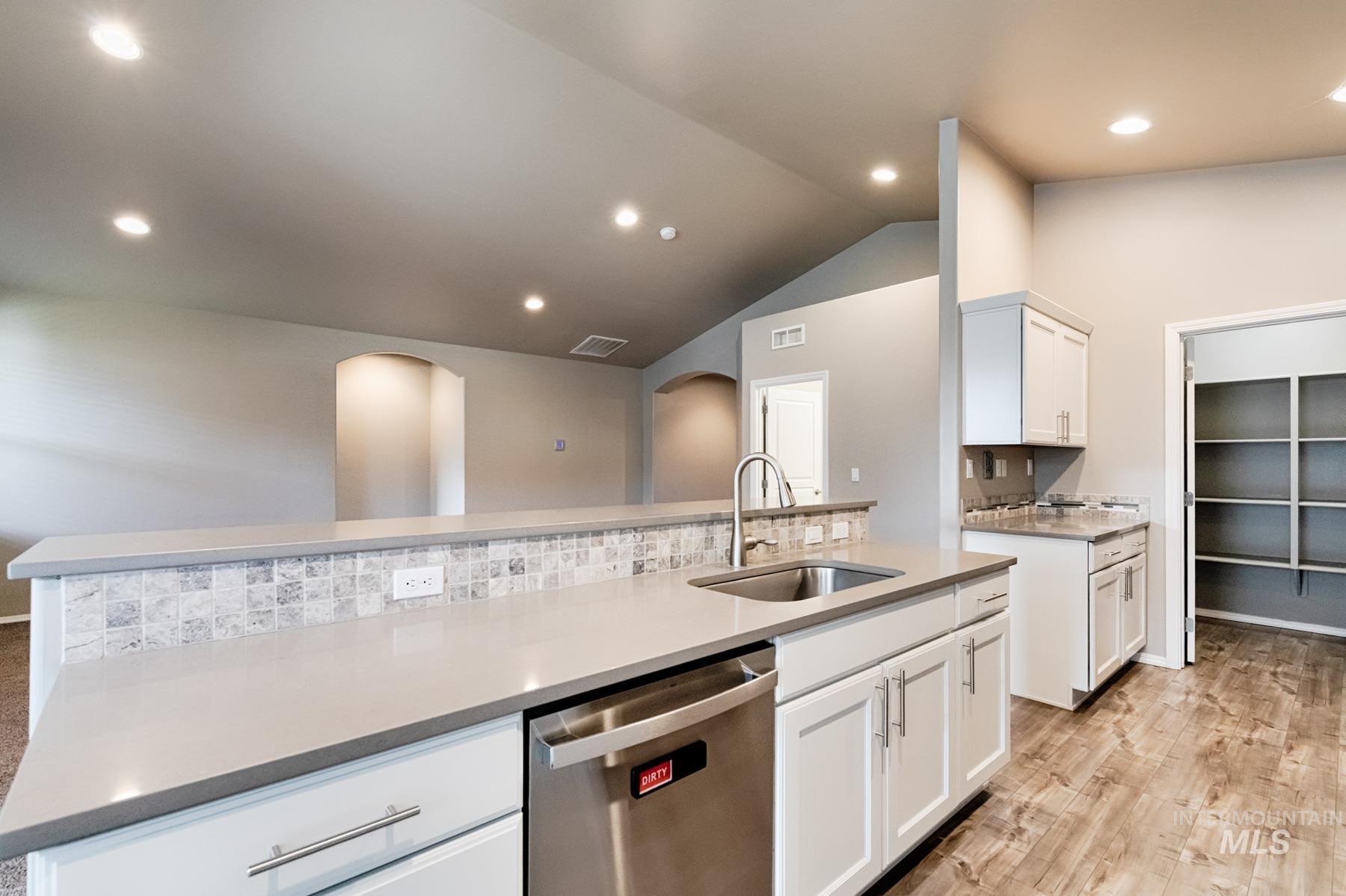 Kitchen featuring dishwasher, white cabinetry, recessed lighting, tasteful backsplash, and light stone counters