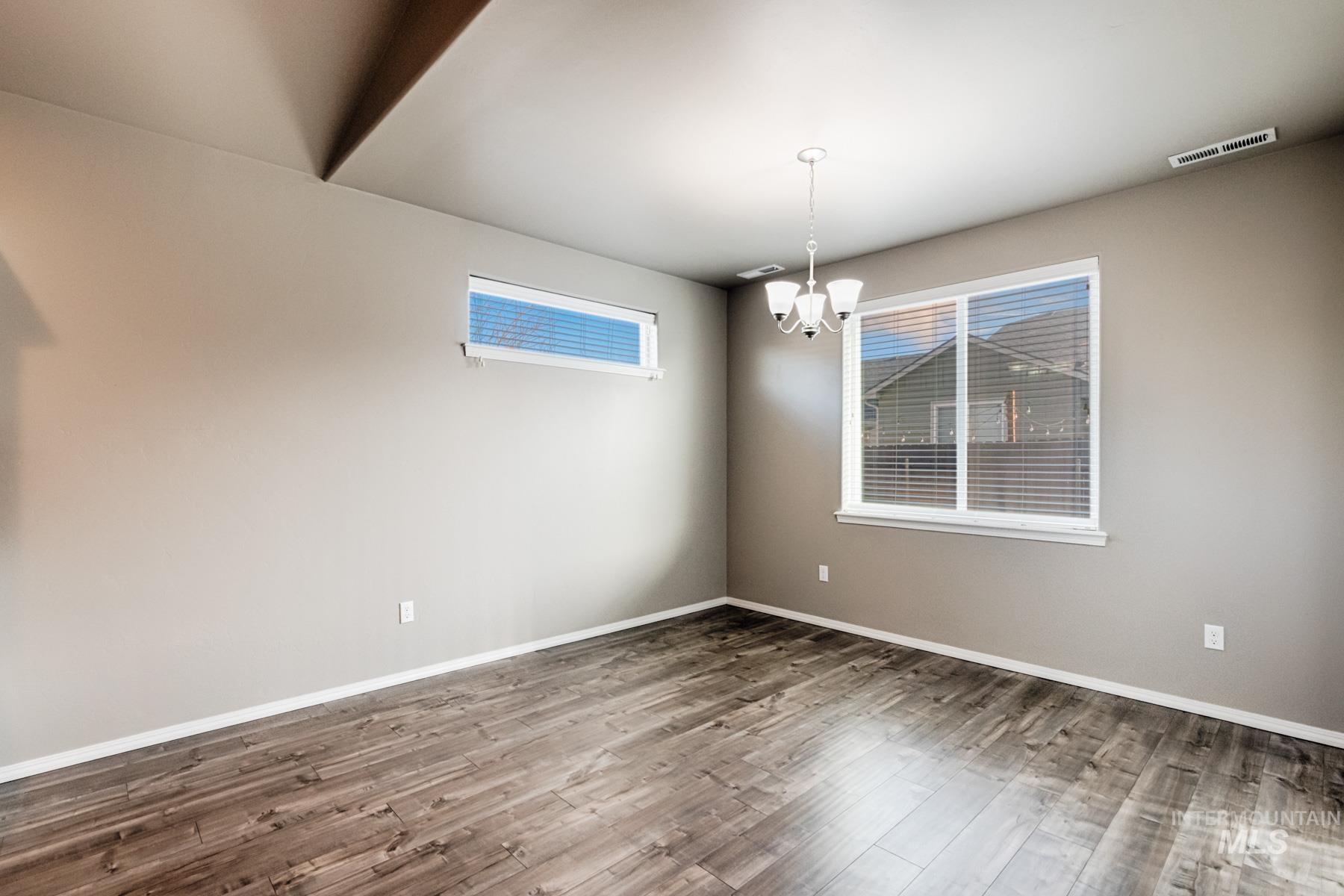 Unfurnished room featuring wood finished floors and a chandelier