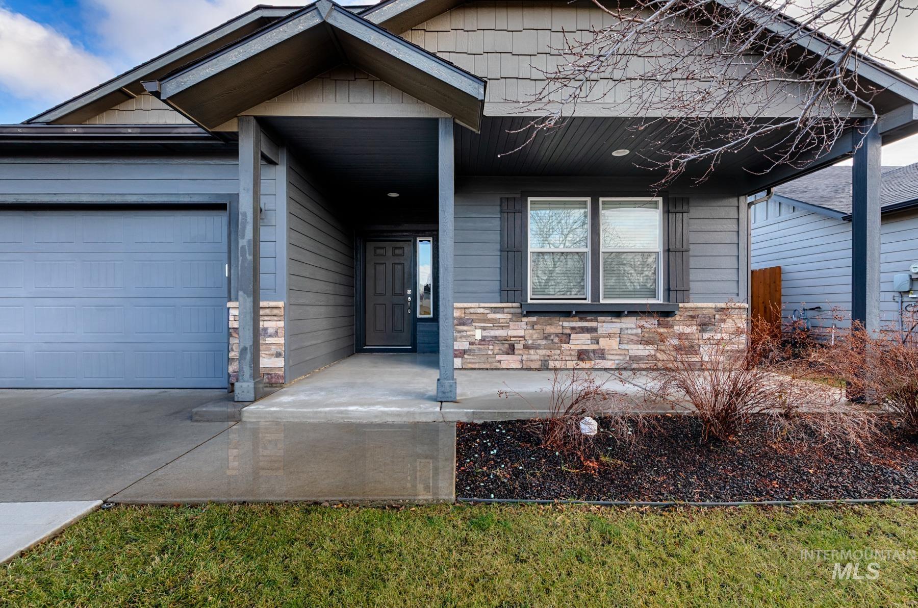 View of front of house with stone siding, a garage, and concrete driveway