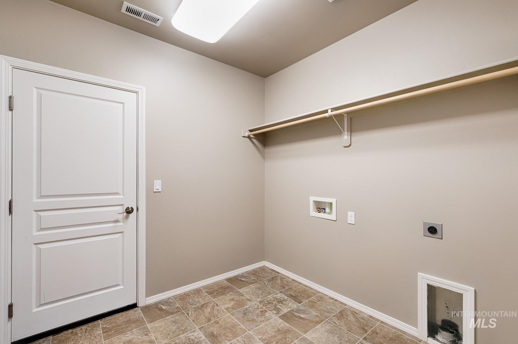 Washroom featuring hookup for a washing machine, hookup for an electric dryer, and stone finish floors