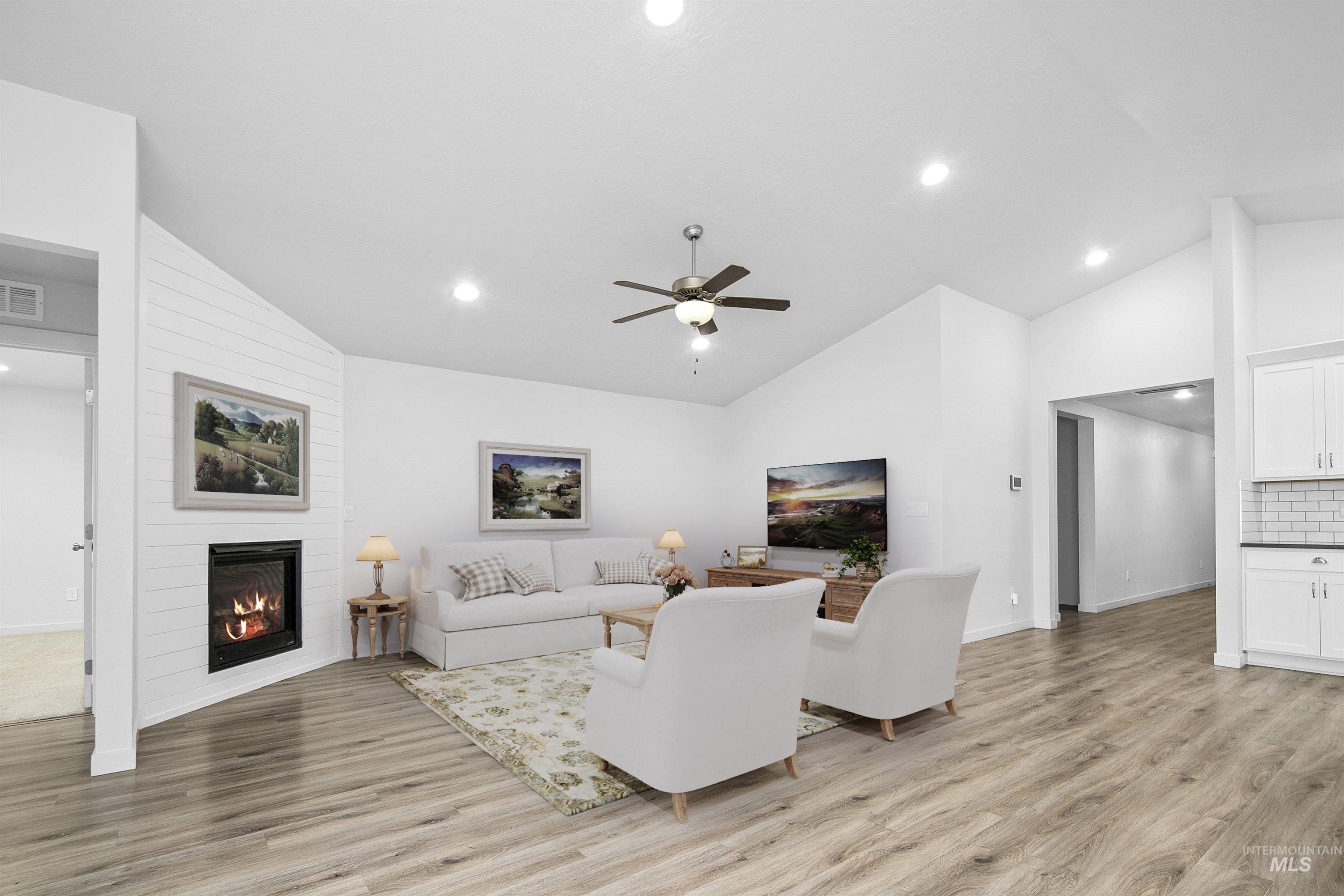 Living area with ceiling fan, light wood-style flooring, a large fireplace, recessed lighting, and high vaulted ceiling