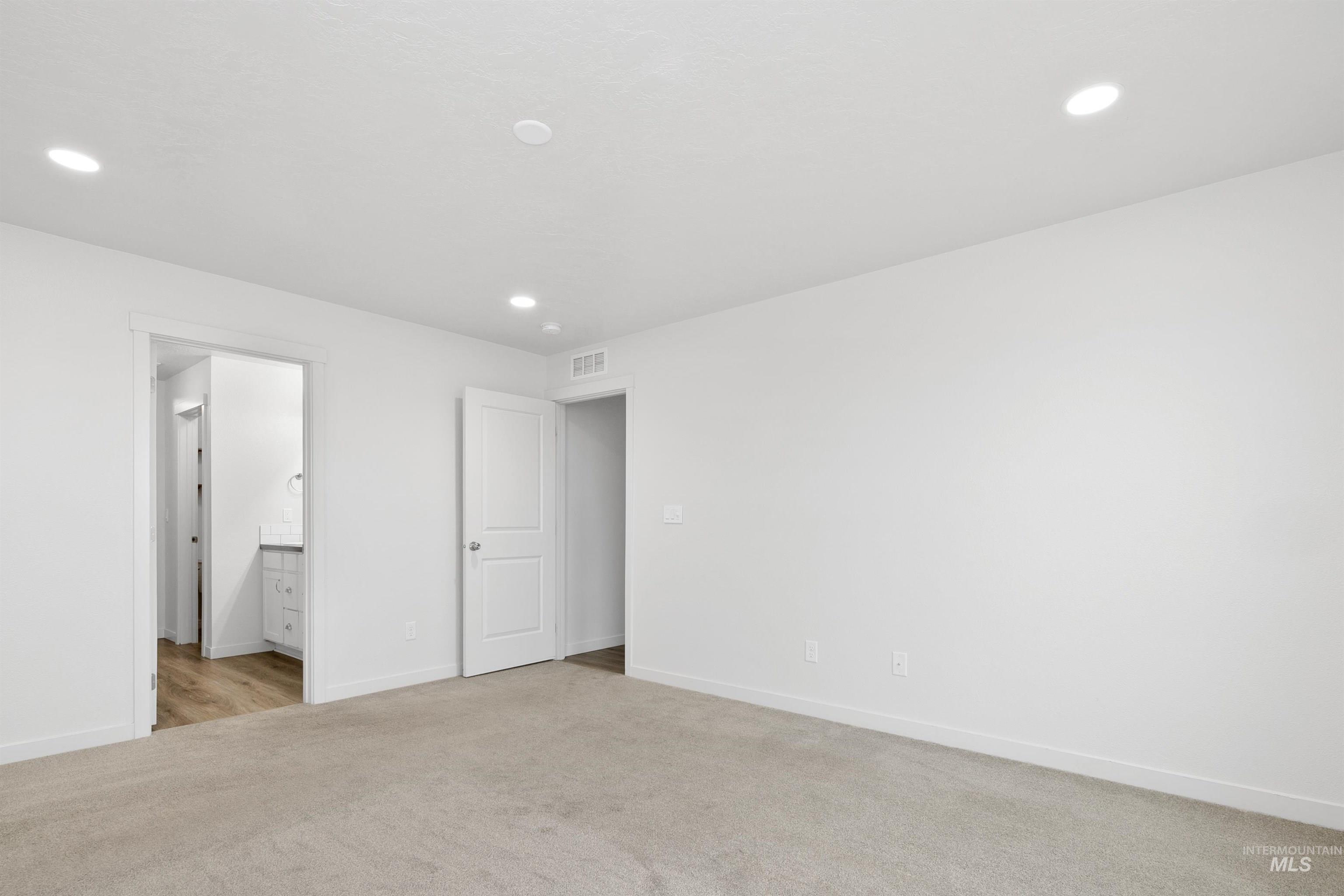 Unfurnished bedroom with light carpet, recessed lighting, and ensuite bath
