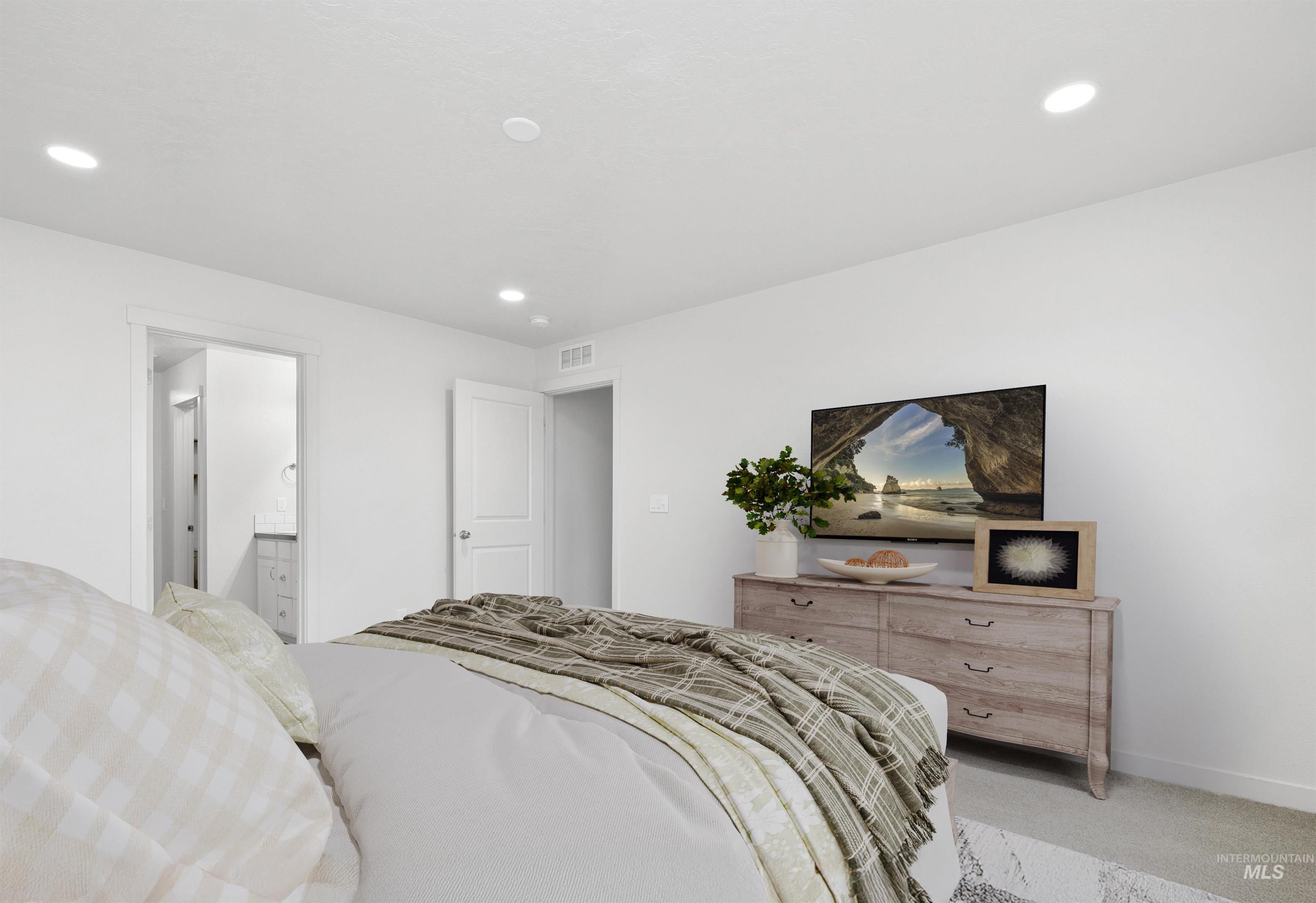 Carpeted bedroom with recessed lighting and ensuite bath