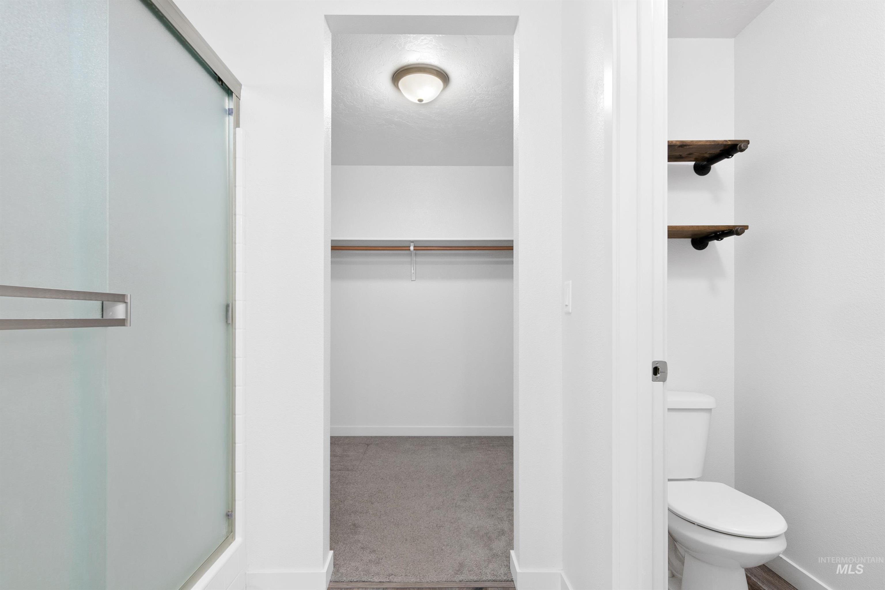 Full bathroom featuring a stall shower, a walk in closet, a textured ceiling, and light colored carpet