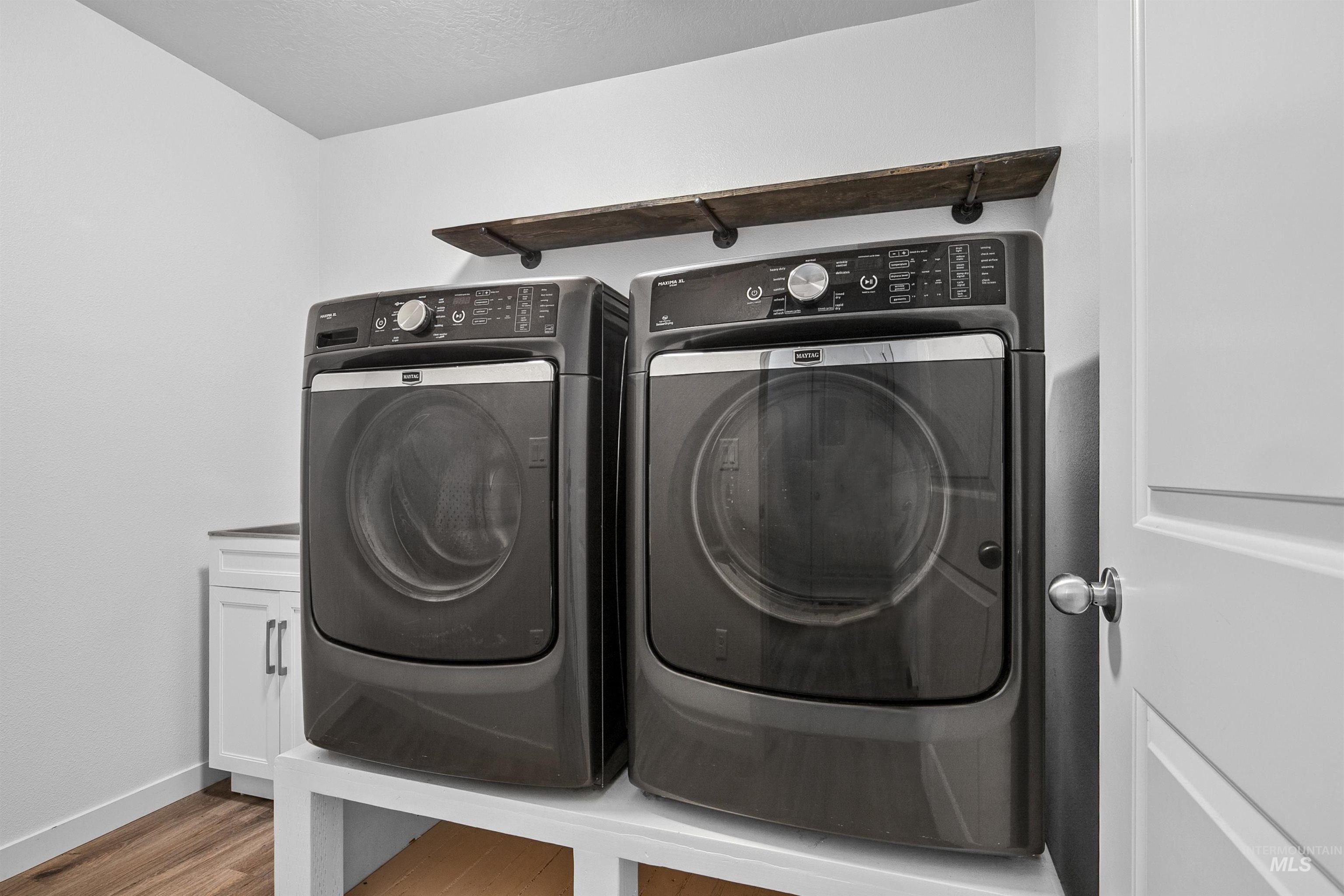 Washroom with light wood-style floors, washing machine and dryer, and cabinet space