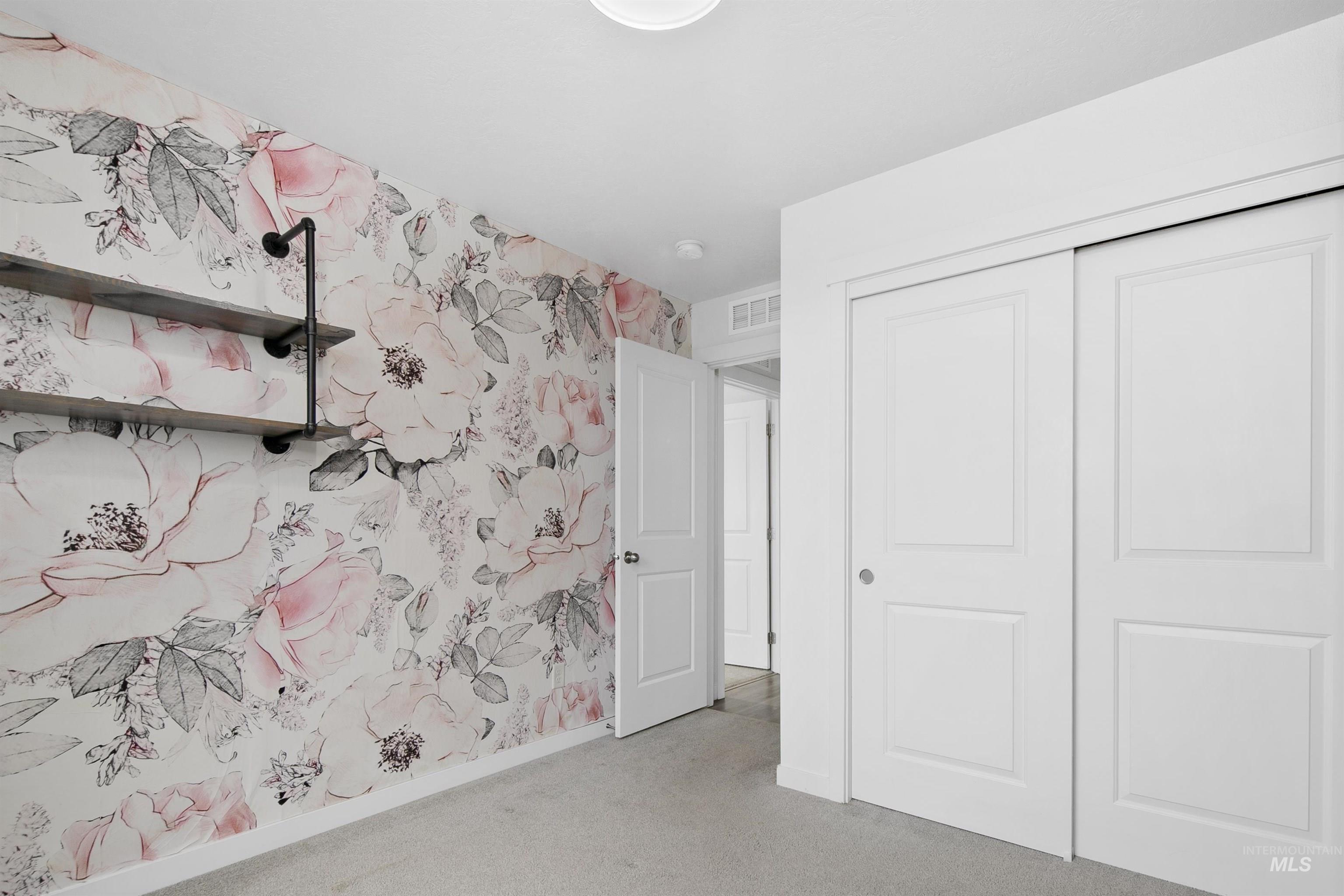 Unfurnished bedroom featuring wallpapered walls, a closet, and light carpet