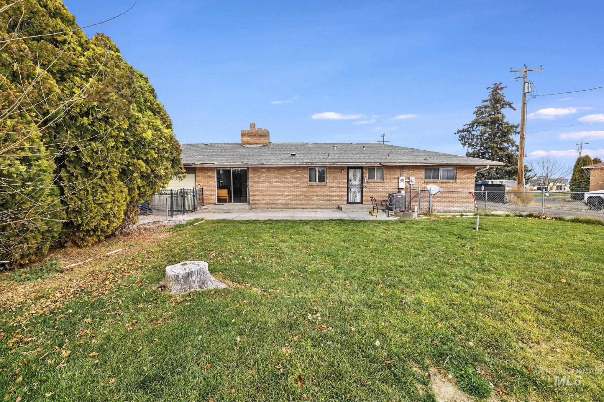 Rear view of house featuring brick siding, a patio, a chimney, and a fenced backyard