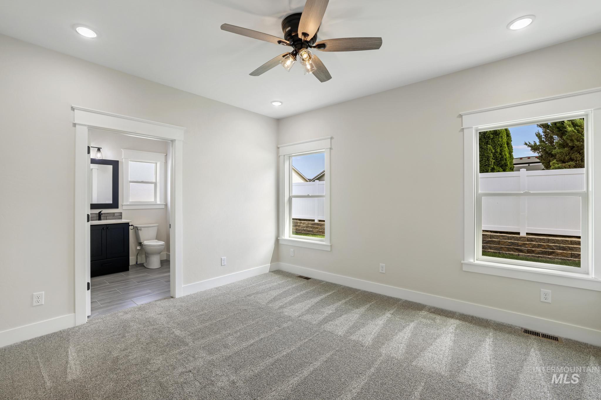 Unfurnished bedroom featuring ceiling fan, ensuite bathroom, recessed lighting, and light carpet