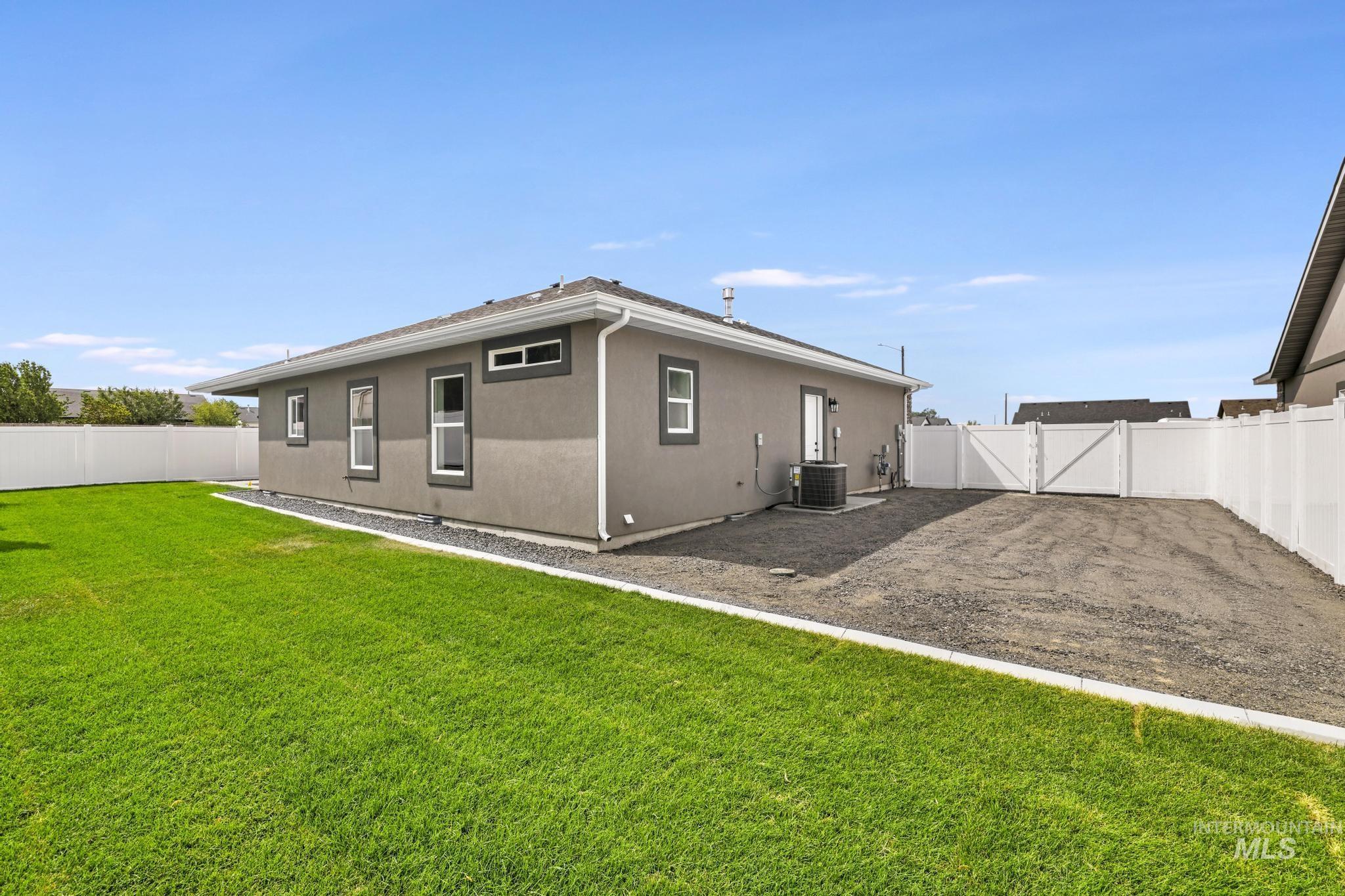Back of property with a fenced backyard, stucco siding, and a gate
