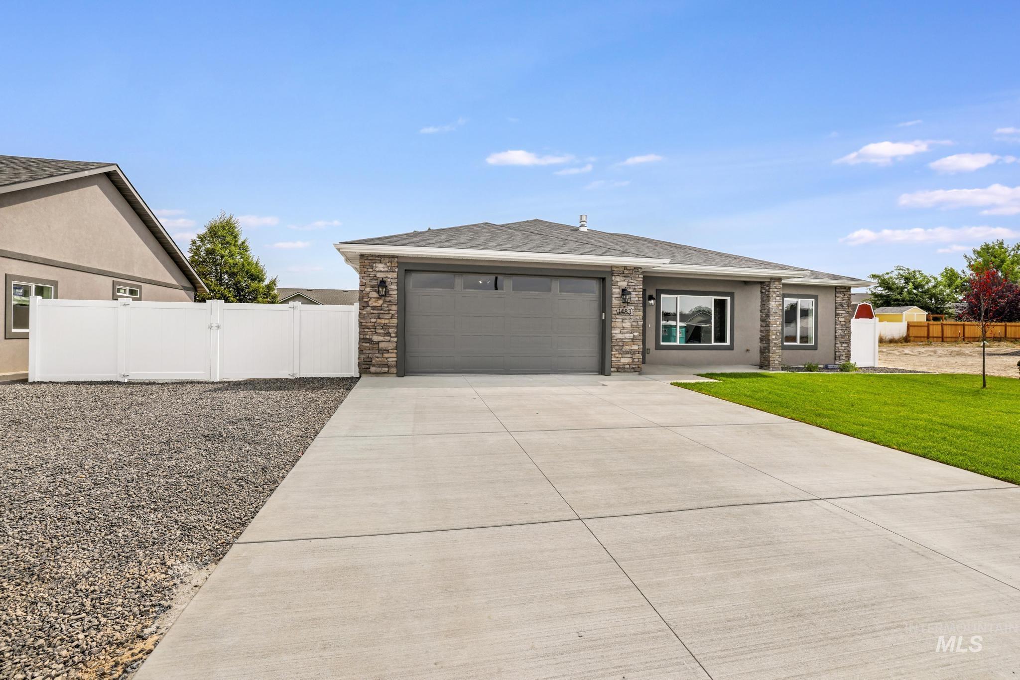 View of front facade with driveway, a gate, an attached garage, roof with shingles, and stucco siding