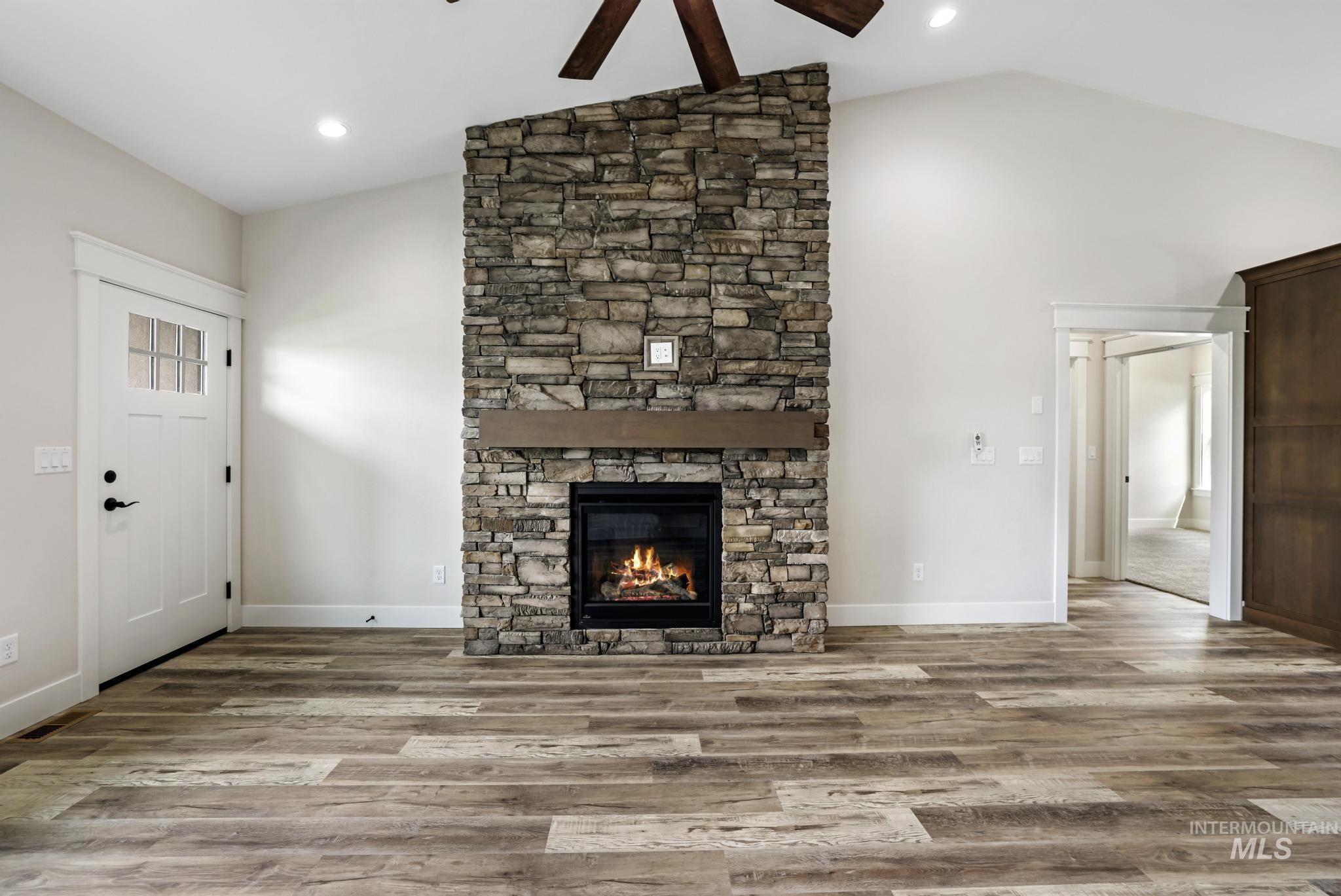 Unfurnished living room with wood finished floors, a fireplace, a ceiling fan, recessed lighting, and high vaulted ceiling
