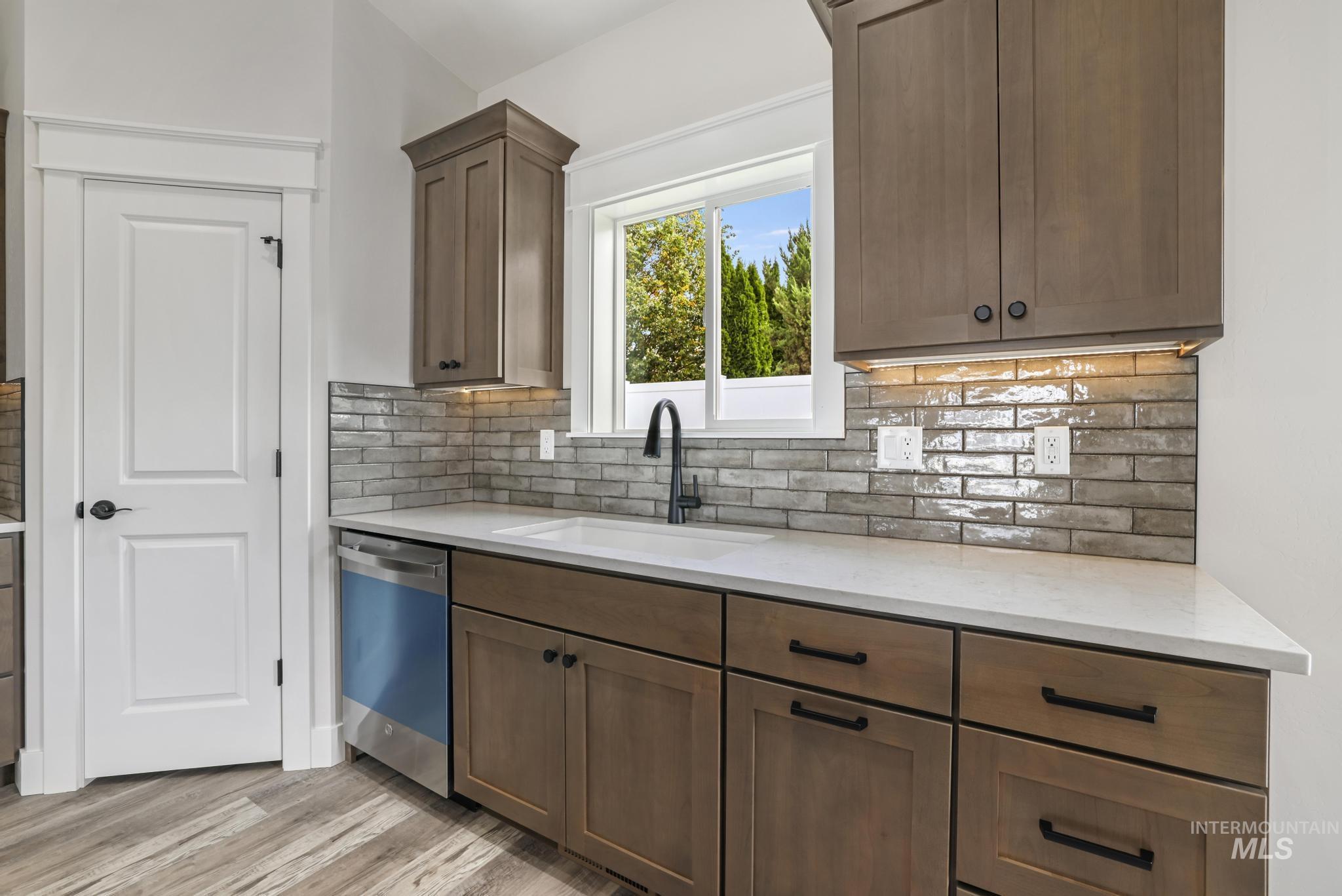 Kitchen featuring light stone counters, dishwasher, and decorative backsplash