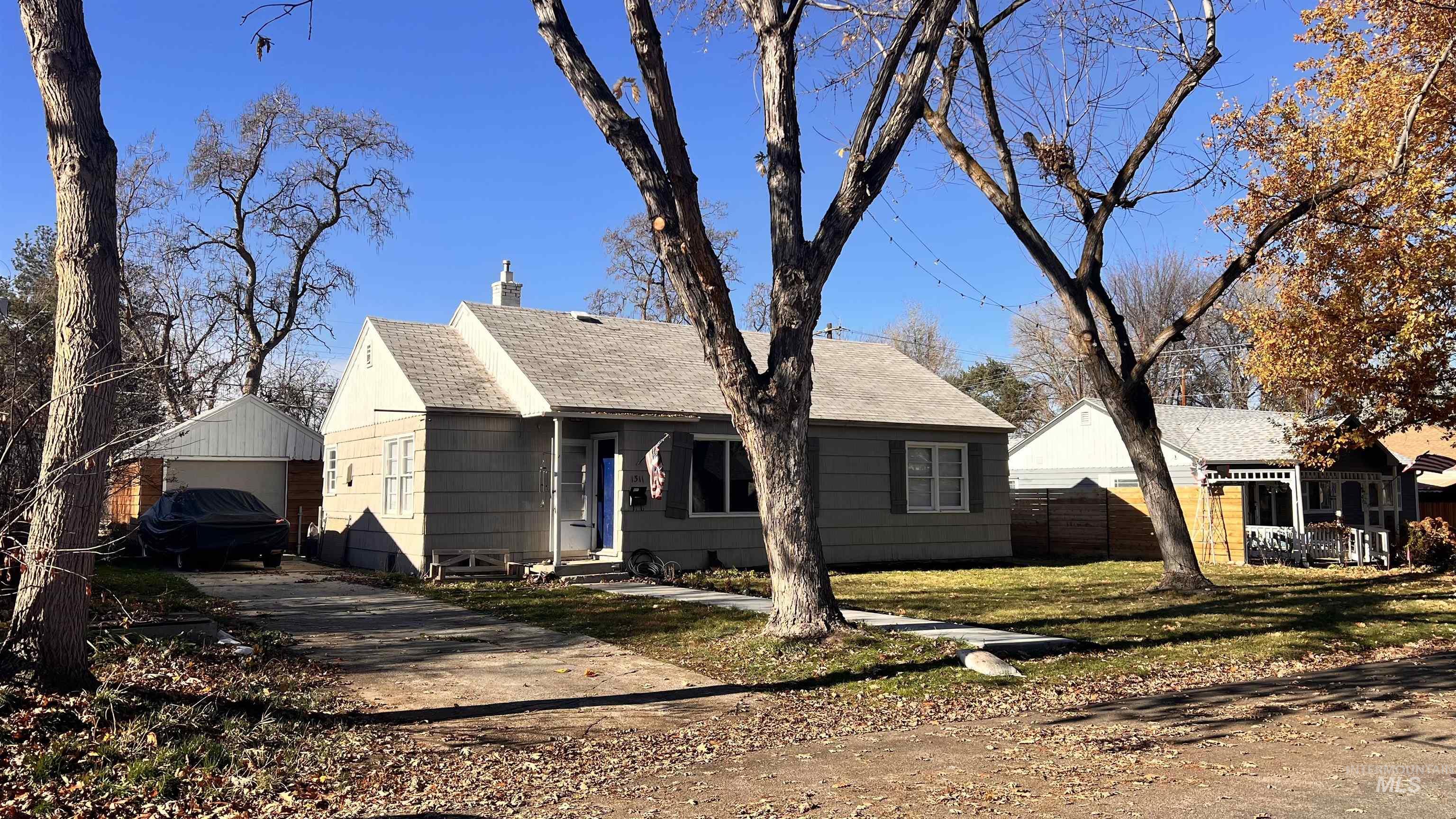 View of front of home with roof with shingles, an outbuilding, driveway, a chimney, and a detached garage