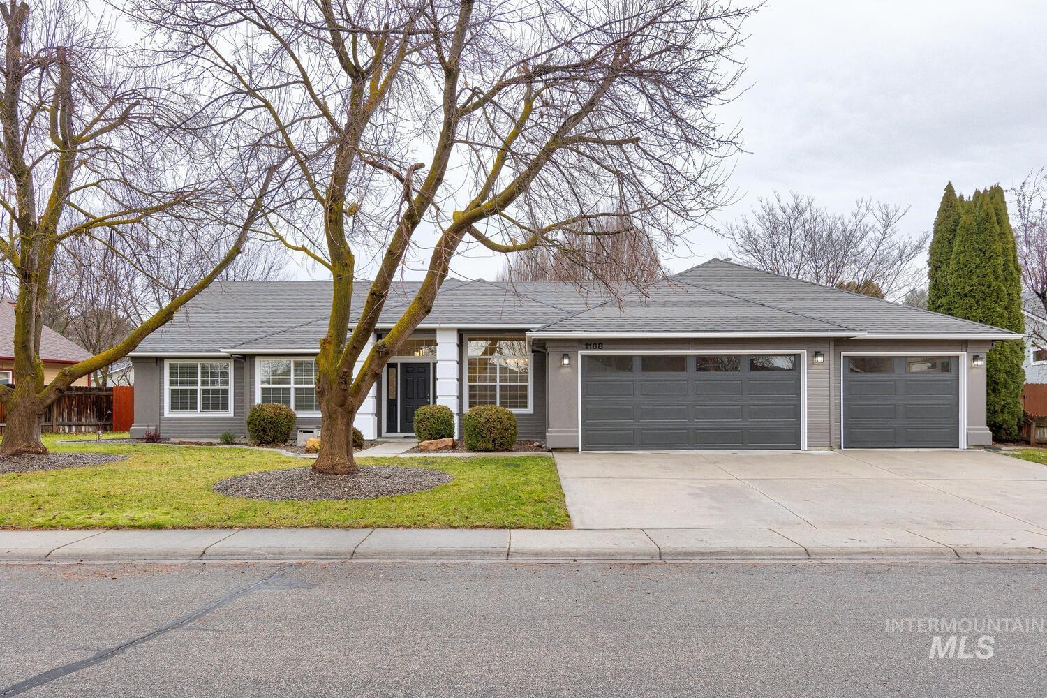 Ranch-style house with driveway, a garage, roof with shingles, and a front lawn