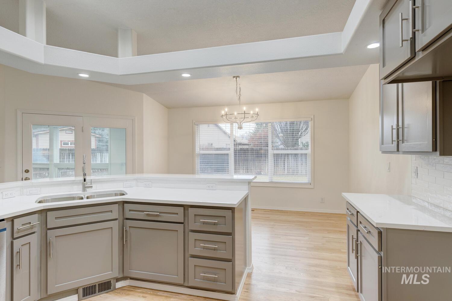Kitchen with gray cabinets, decorative light fixtures, light wood-style flooring, recessed lighting, and a chandelier