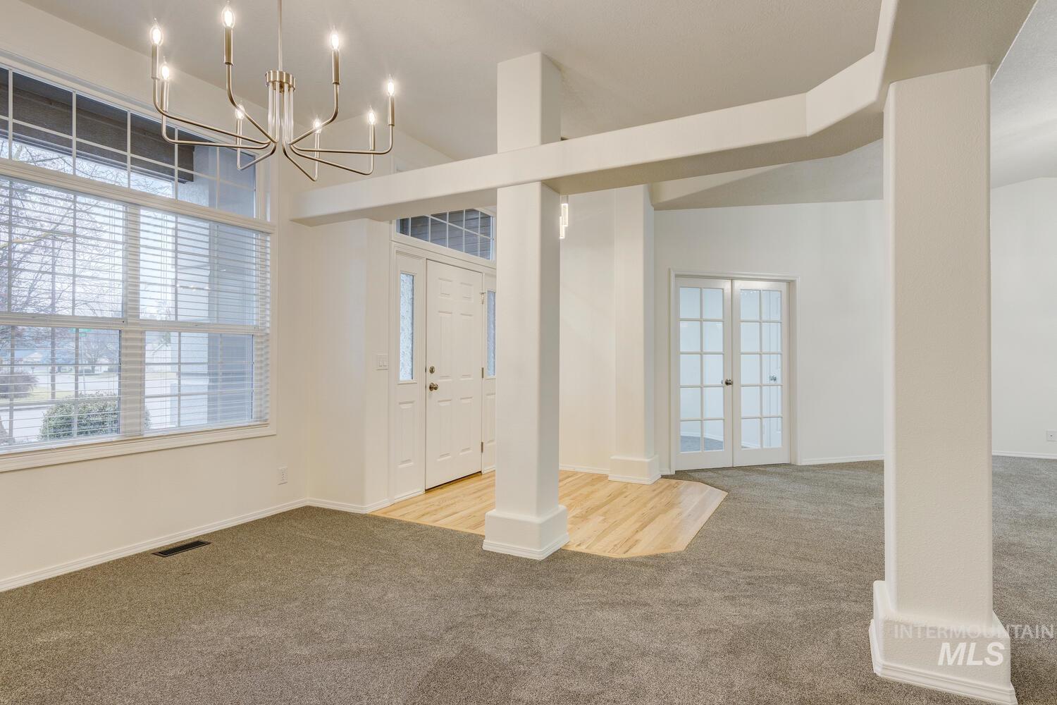 Carpeted entrance foyer with healthy amount of natural light, french doors, and a chandelier