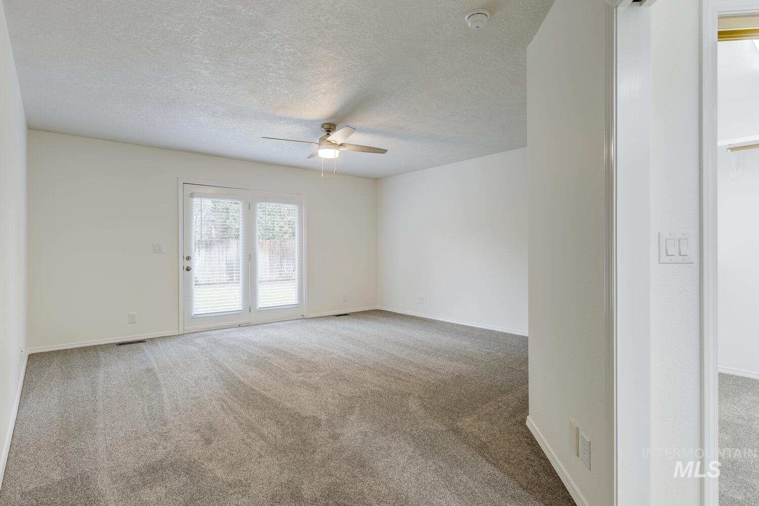 Spare room with light colored carpet, a textured ceiling, and a ceiling fan