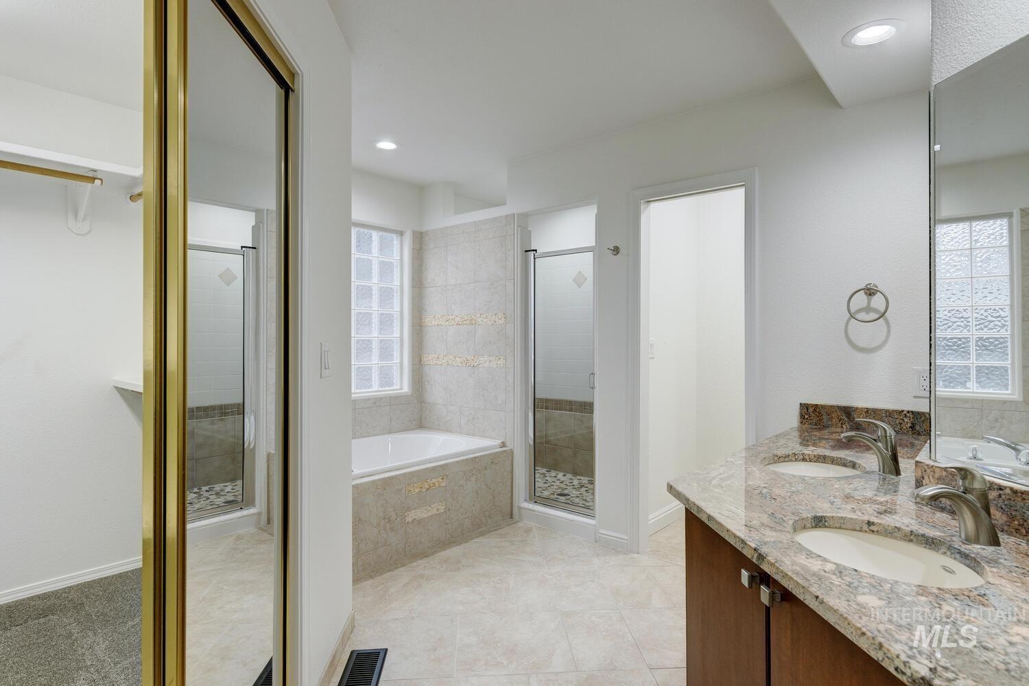 Bathroom with a bath, double vanity, a stall shower, recessed lighting, and light tile patterned flooring