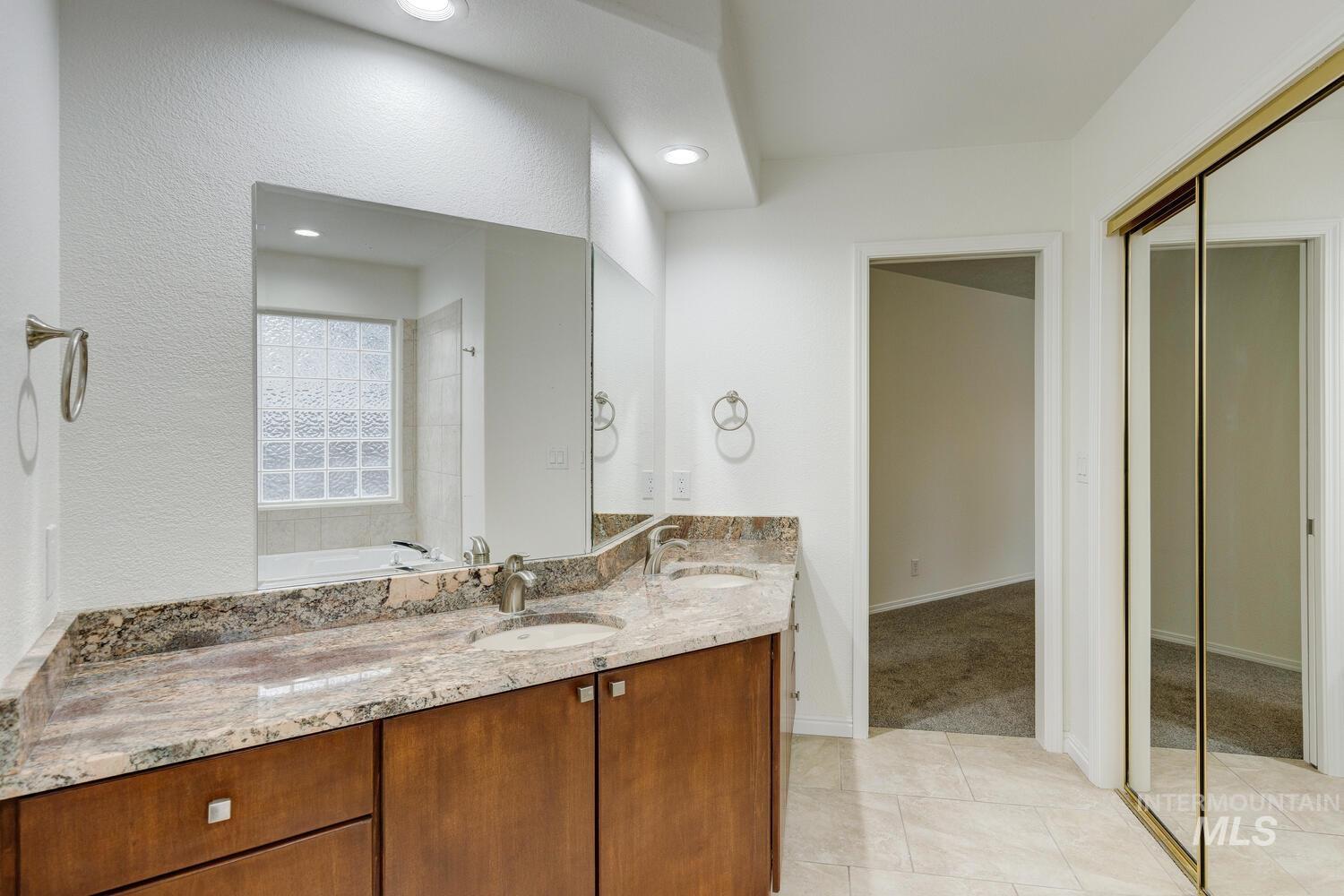 Bathroom featuring double vanity, light tile patterned floors, and recessed lighting