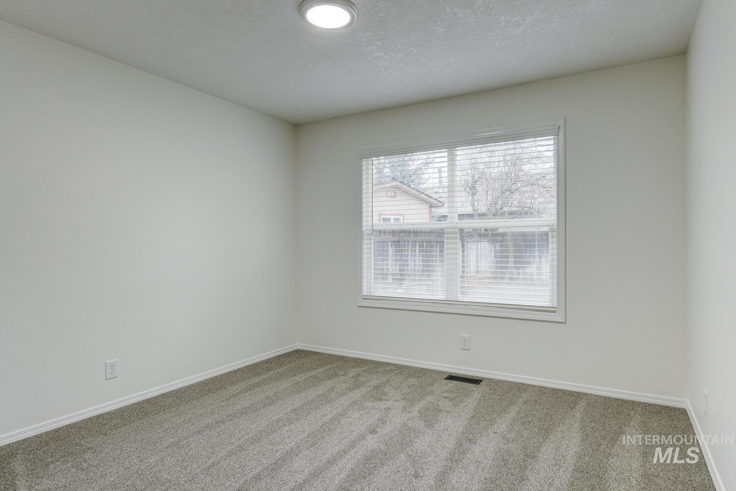 Carpeted spare room featuring a textured ceiling and baseboards