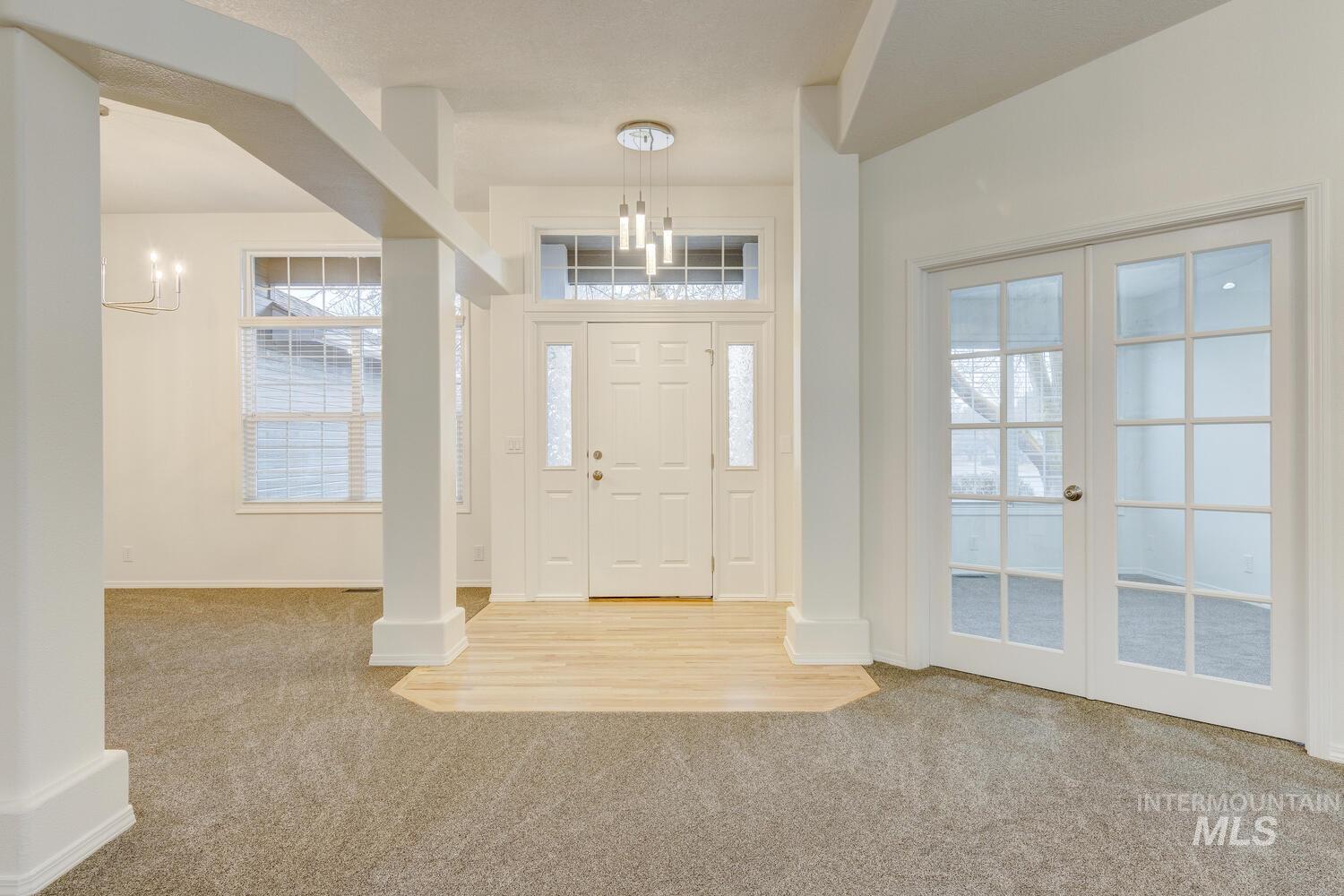 Carpeted entryway featuring french doors and baseboards