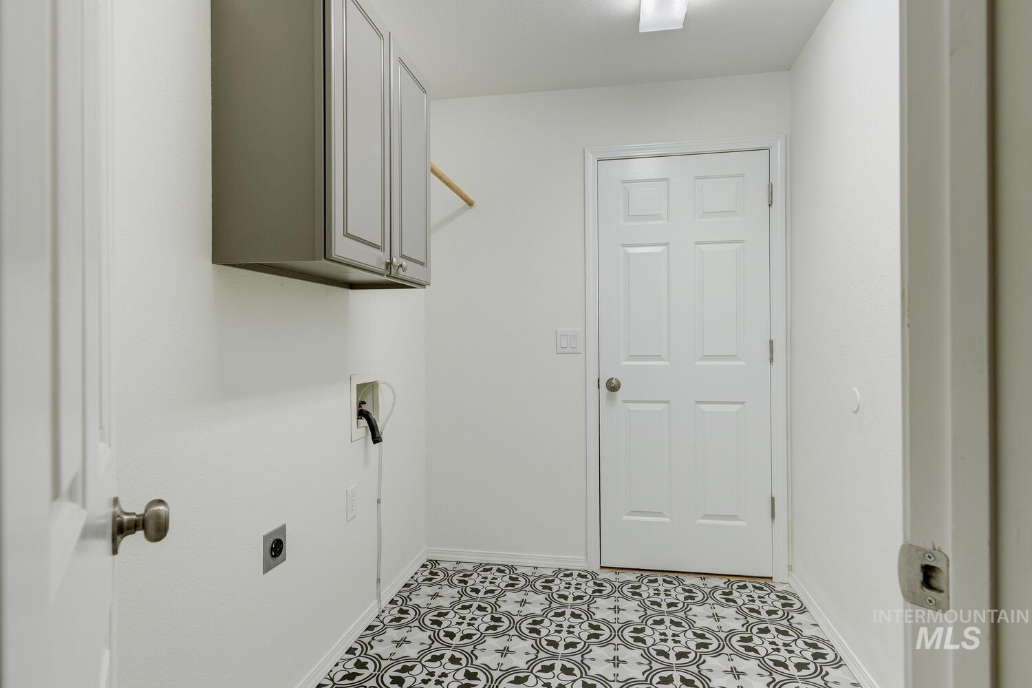 Laundry area with hookup for an electric dryer, hookup for a washing machine, cabinet space, and light tile patterned floors