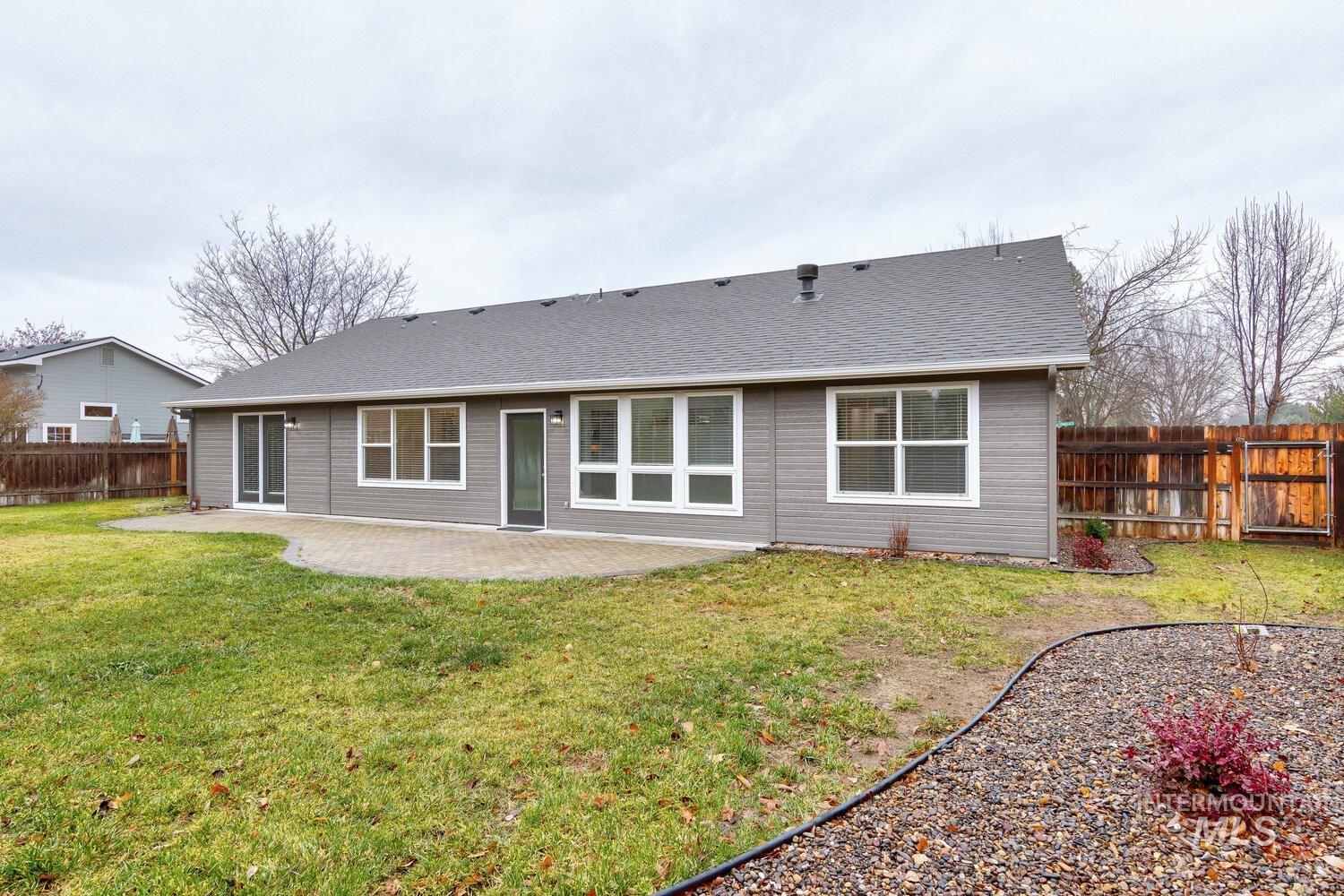 Back of property featuring a fenced backyard, a patio area, and a shingled roof