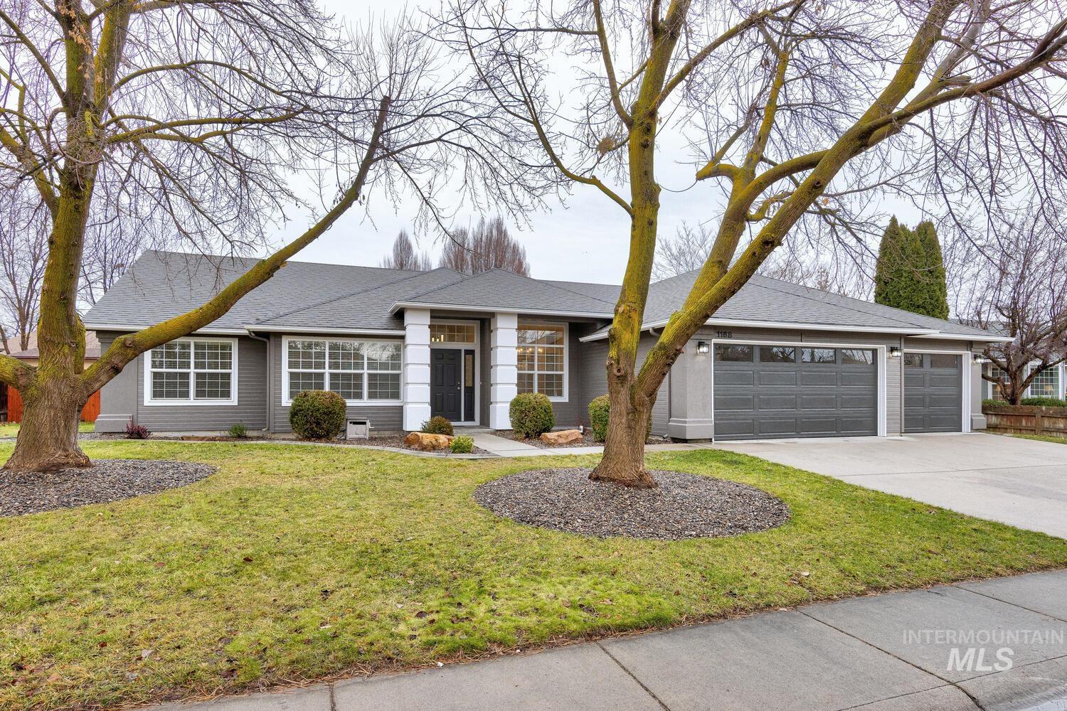Ranch-style house with driveway, a garage, roof with shingles, and a front lawn