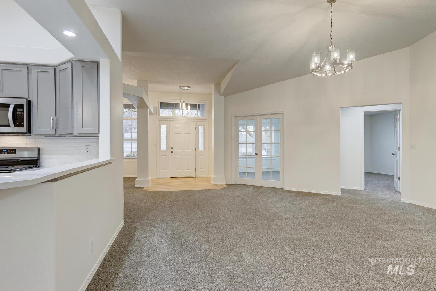 Entrance foyer featuring light colored carpet, a chandelier, and vaulted ceiling