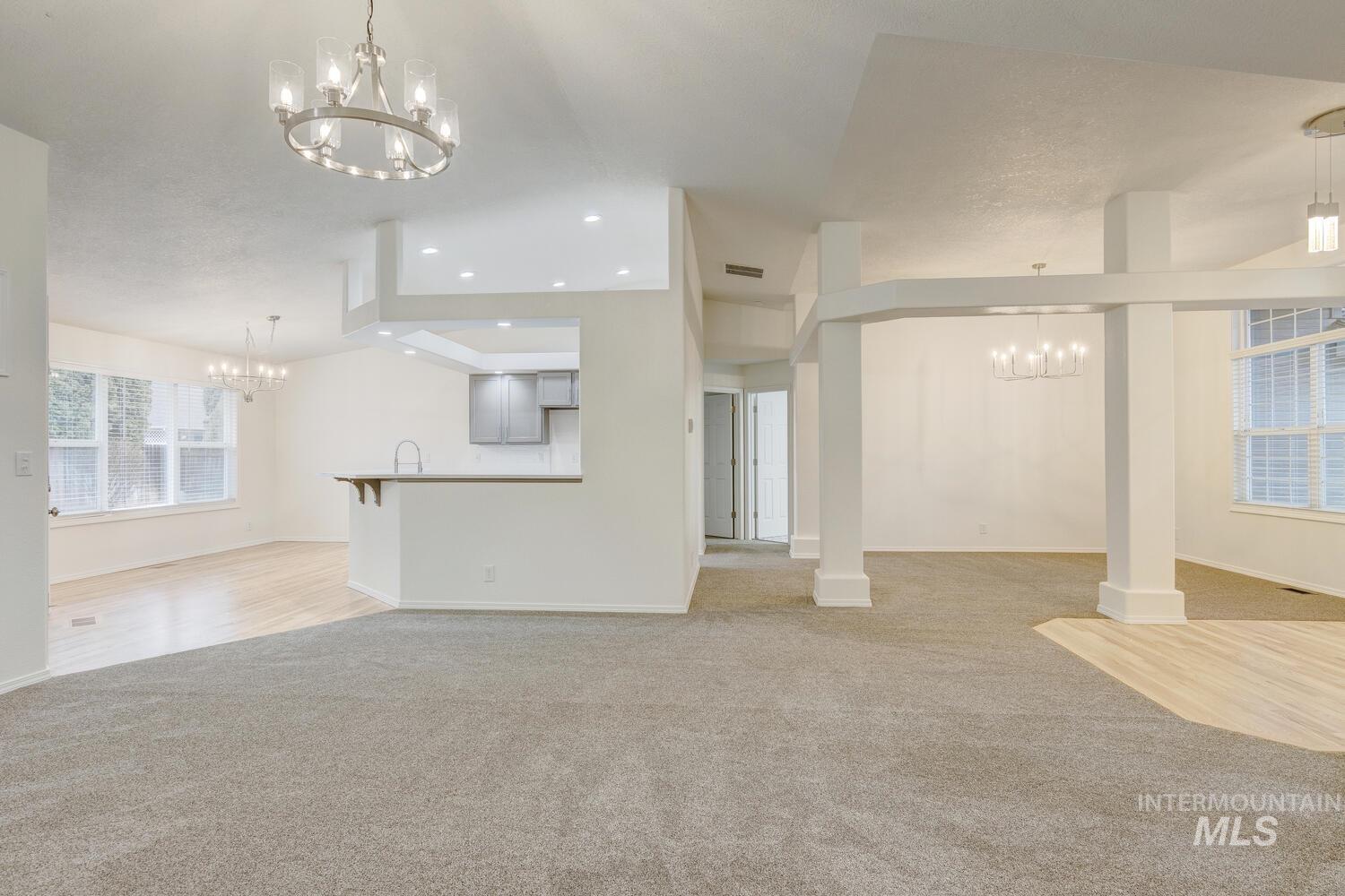 Unfurnished living room featuring a chandelier, light carpet, and recessed lighting