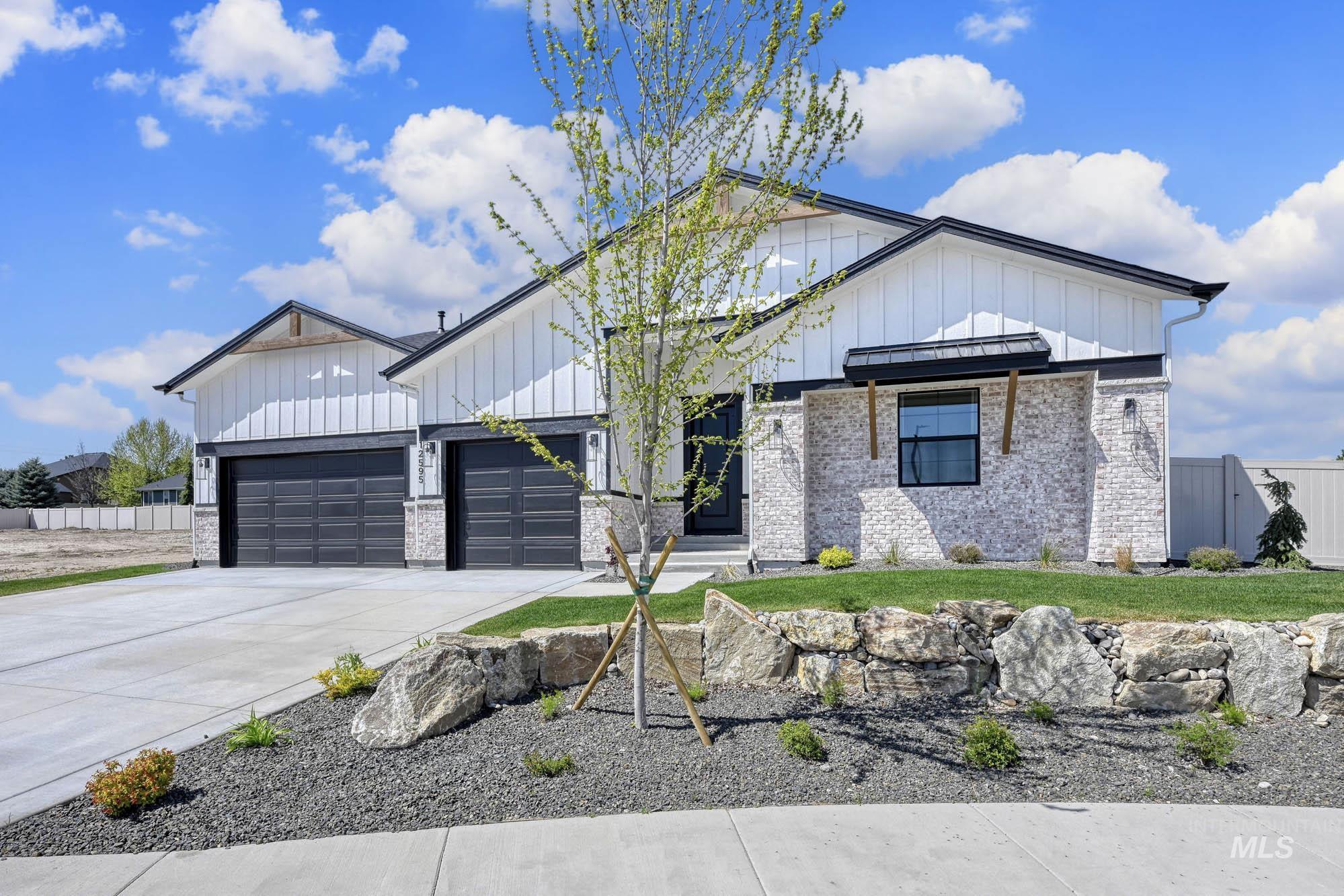 Modern farmhouse style home with board and batten siding, driveway, brick siding, and an attached garage