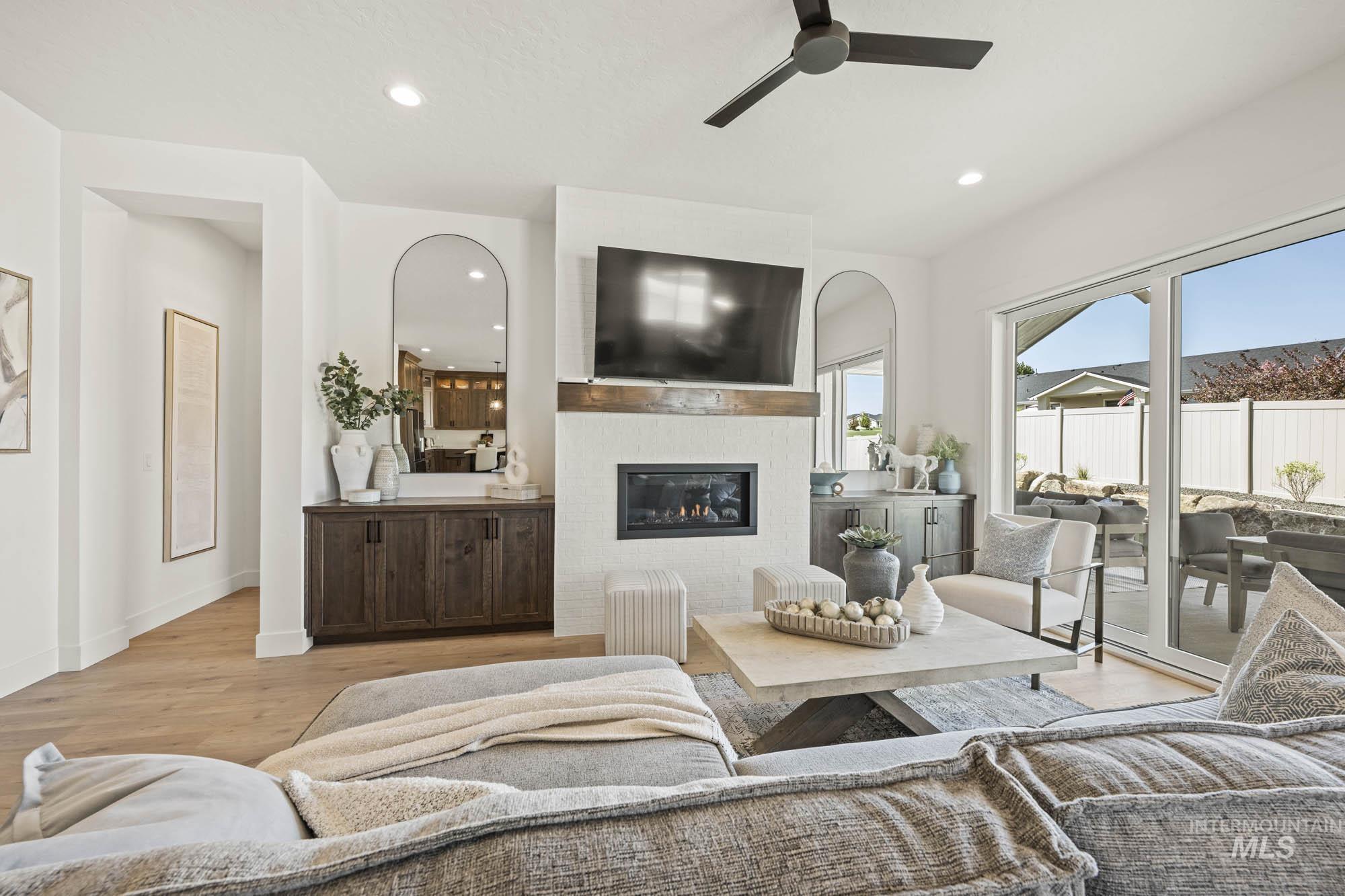 Living area featuring a glass covered fireplace, light wood-style flooring, recessed lighting, and a ceiling fan