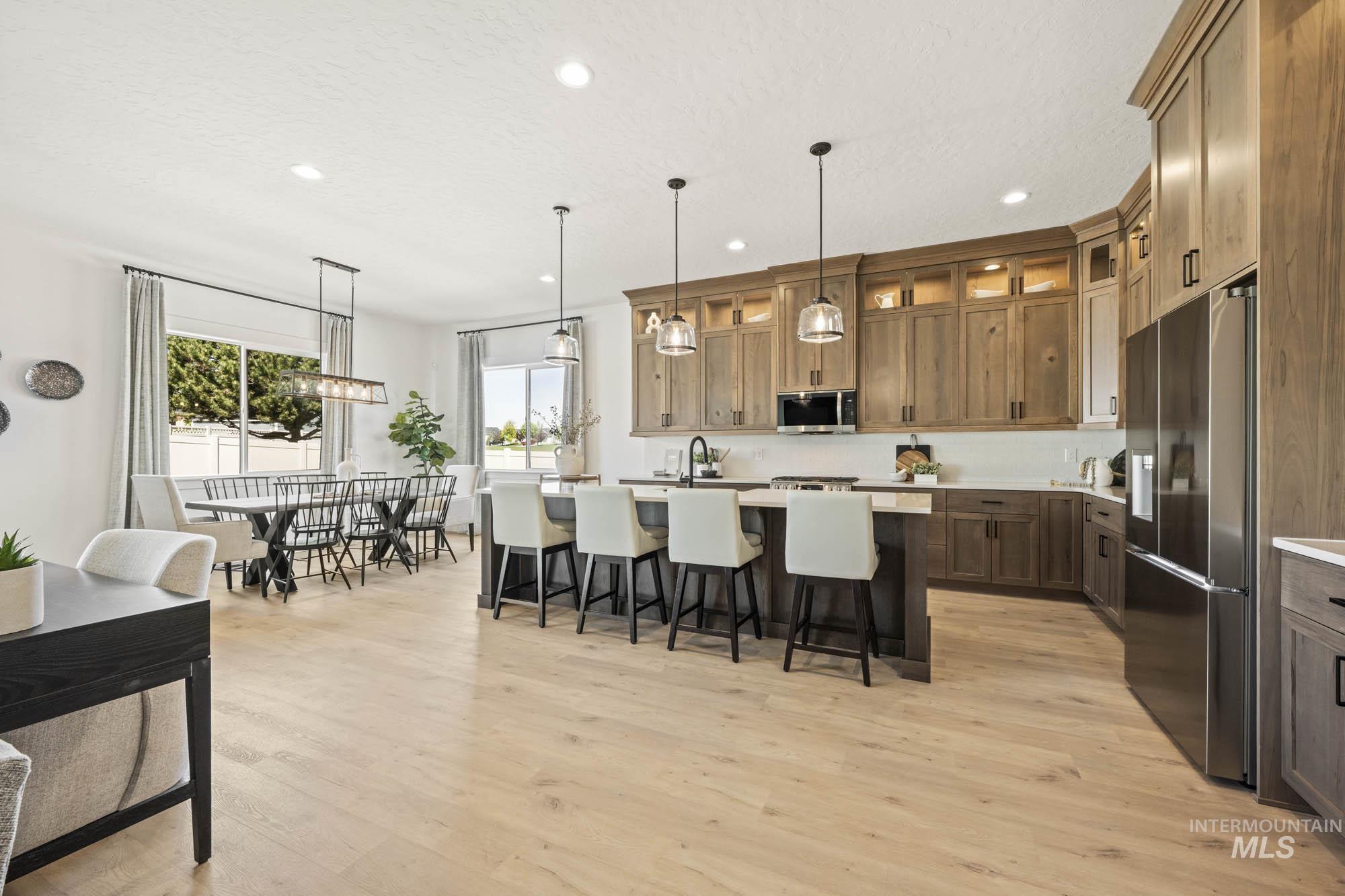 Kitchen with a breakfast bar, hanging light fixtures, an island with sink, appliances with stainless steel finishes, and recessed lighting
