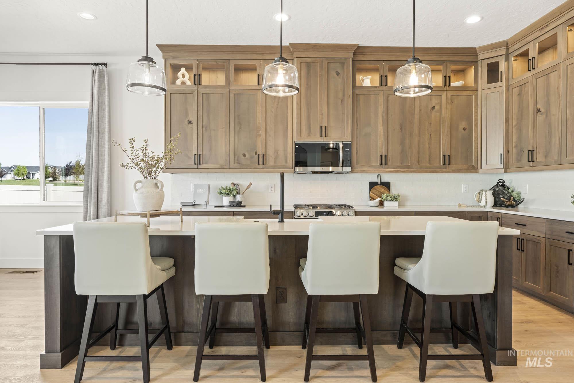 Kitchen with light wood-type flooring, a kitchen island with sink, a kitchen bar, pendant lighting, and recessed lighting