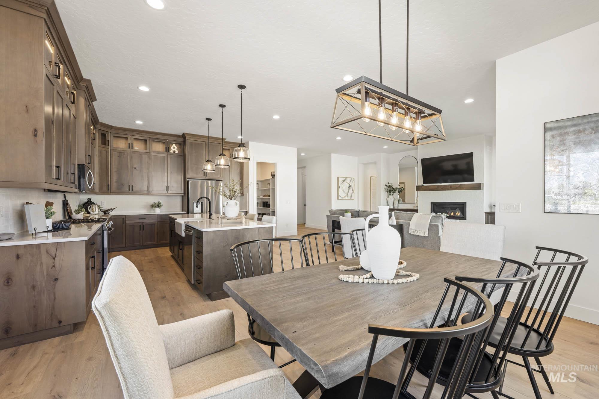 Dining space featuring light wood finished floors, a glass covered fireplace, and recessed lighting