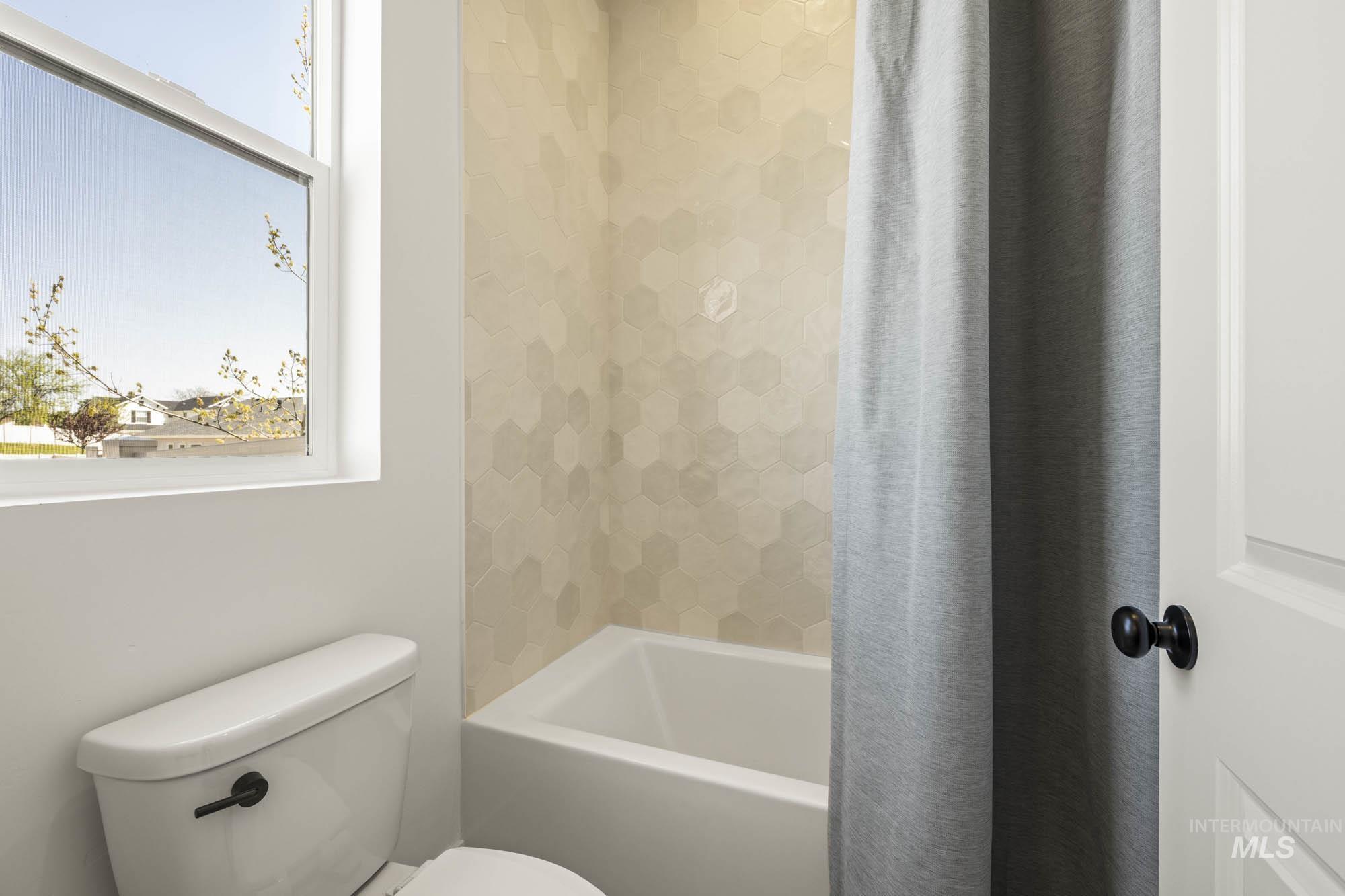 Bathroom featuring shower / bath combo with shower curtain and plenty of natural light
